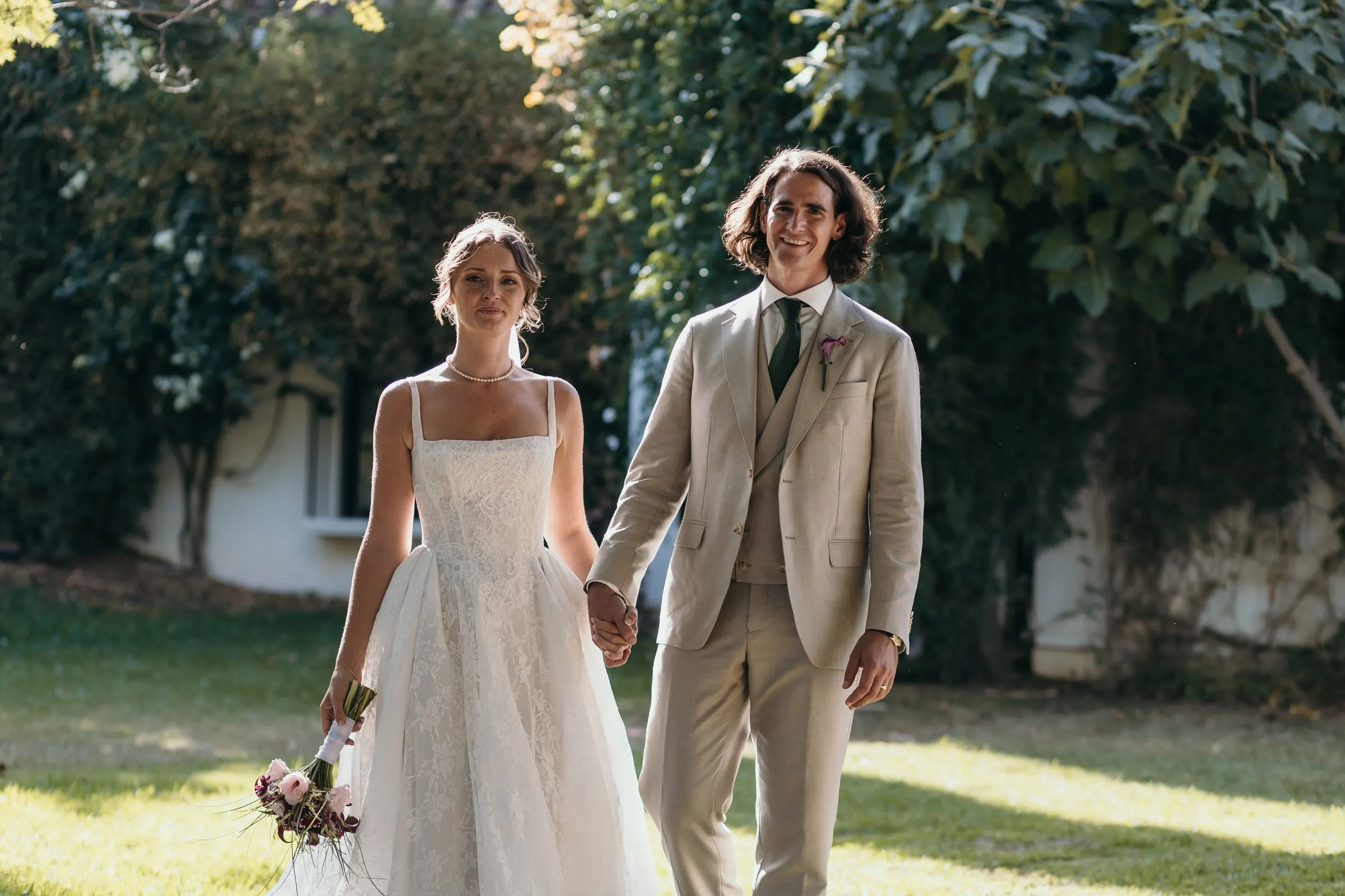 Bride and groom walking hand in hand across the garden lawn in the sun, Hacienda San José, Mijas