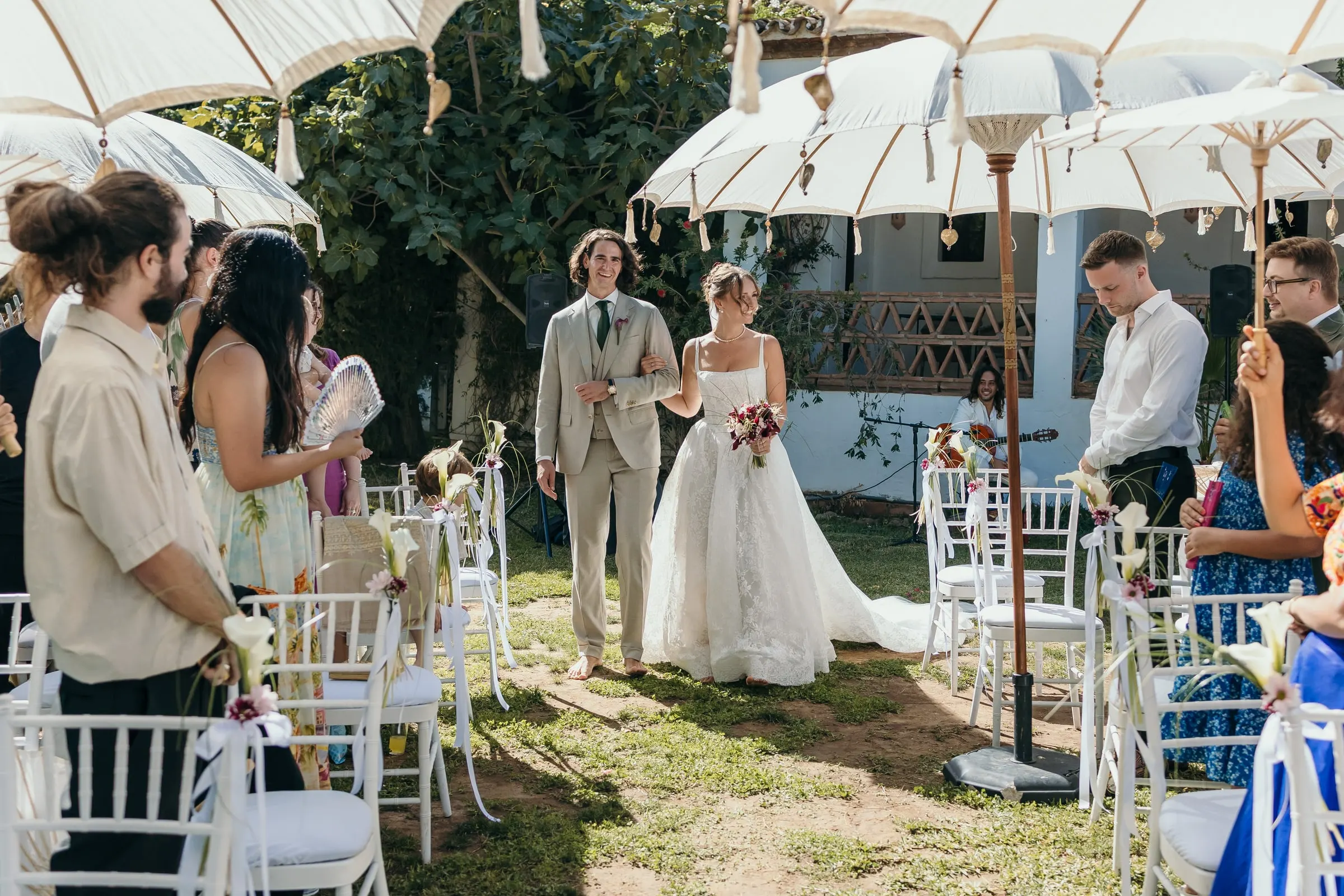 The bride walking down the aisle on a man's arm under white parasols, Hacienda San José, Mijas