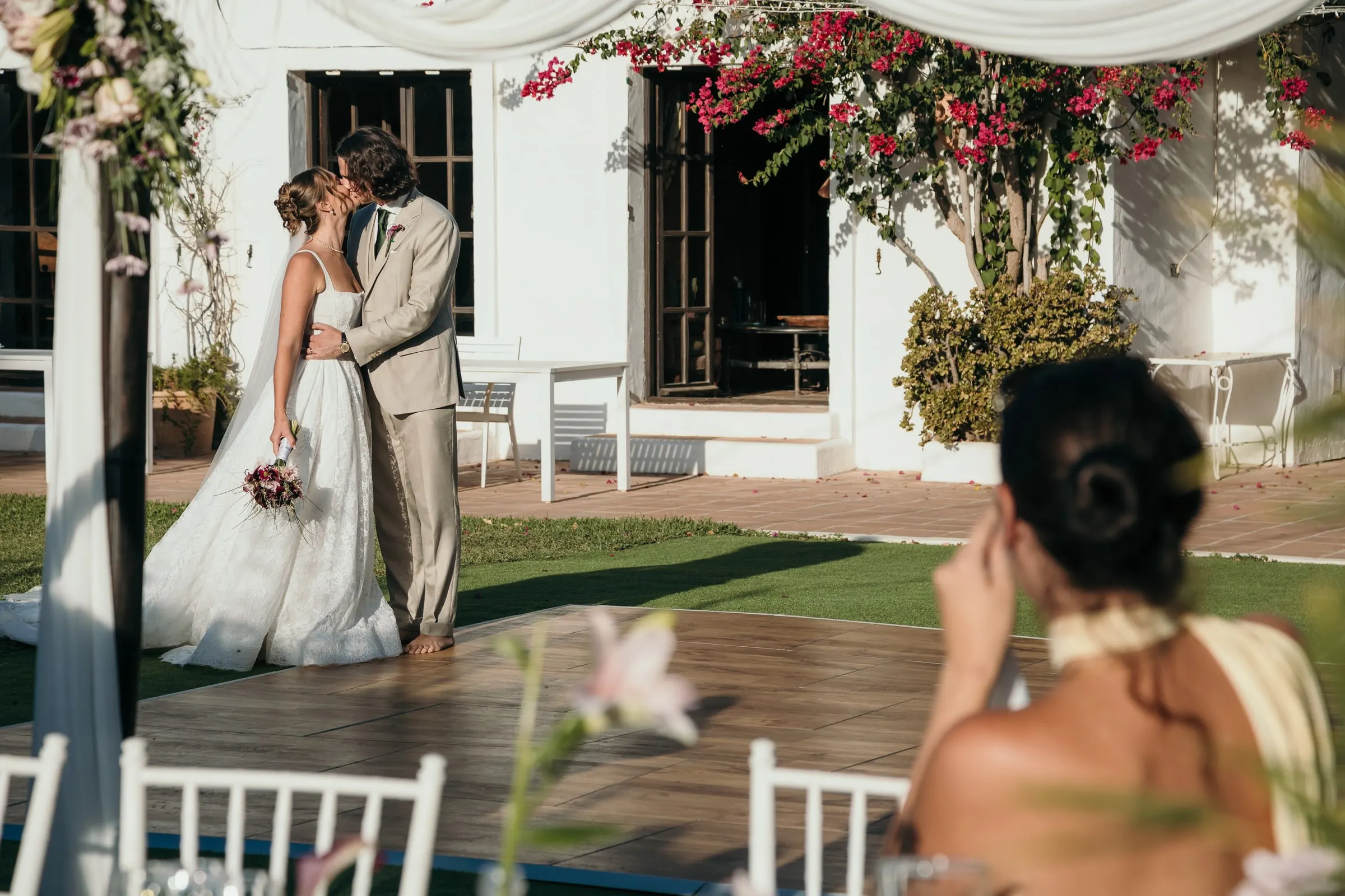 The couple kissing on the lawn as a guest in the foreground wipes away a tear, Hacienda San José, Mijas