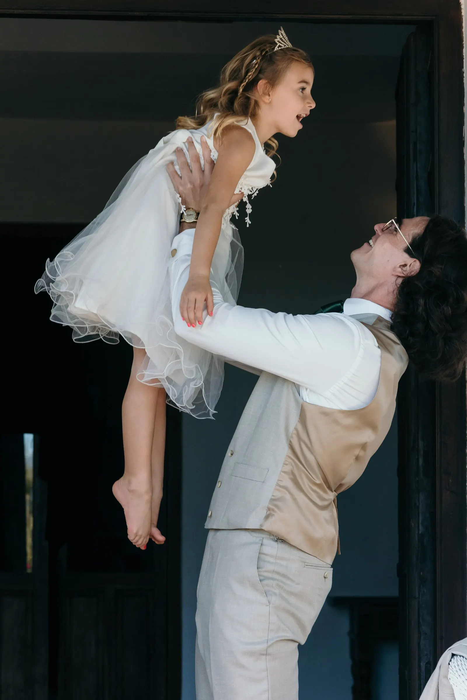 The groom lifting the laughing flower girl high in the air in a doorway, Hacienda San José, Mijas