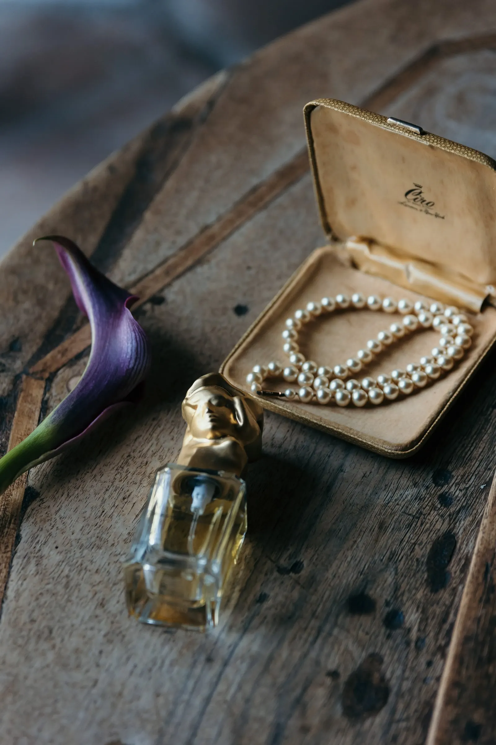 Pearls in a vintage case beside a perfume bottle and a purple calla lily, Hacienda San José, Mijas