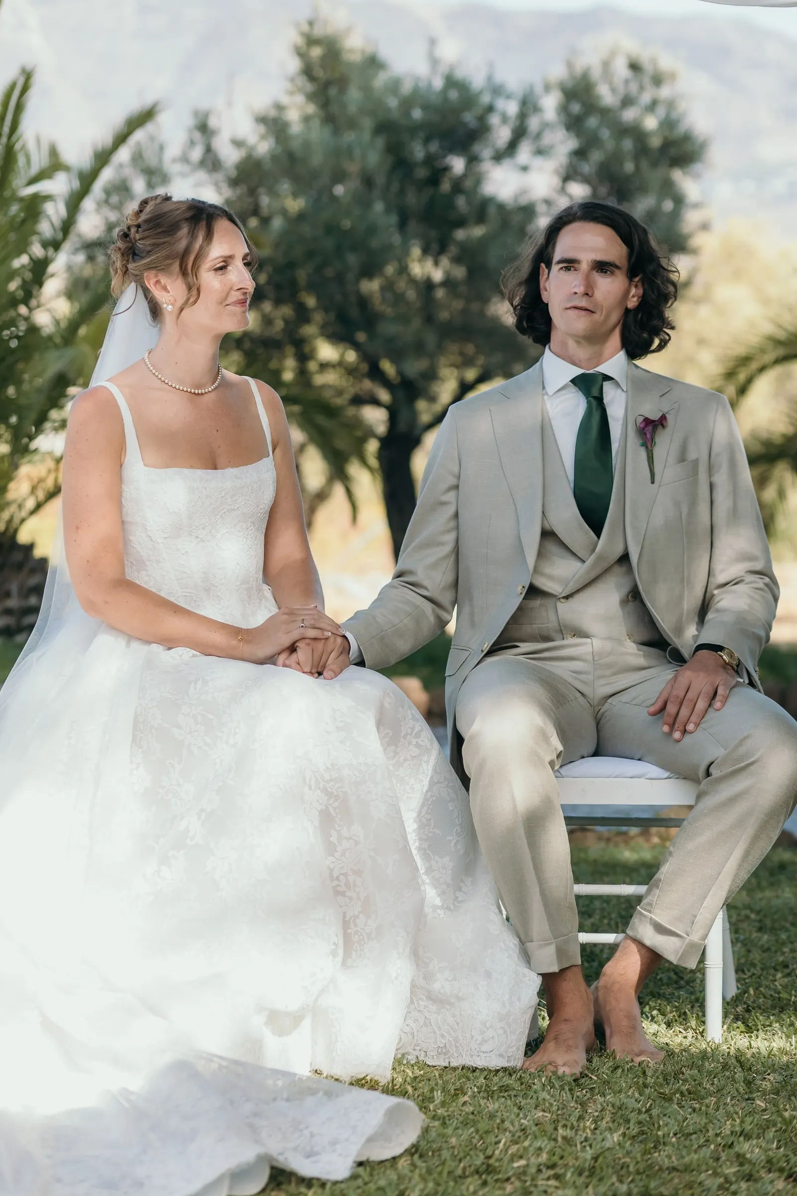 Bride and groom seated holding hands during the ceremony, both smiling, Hacienda San José, Mijas