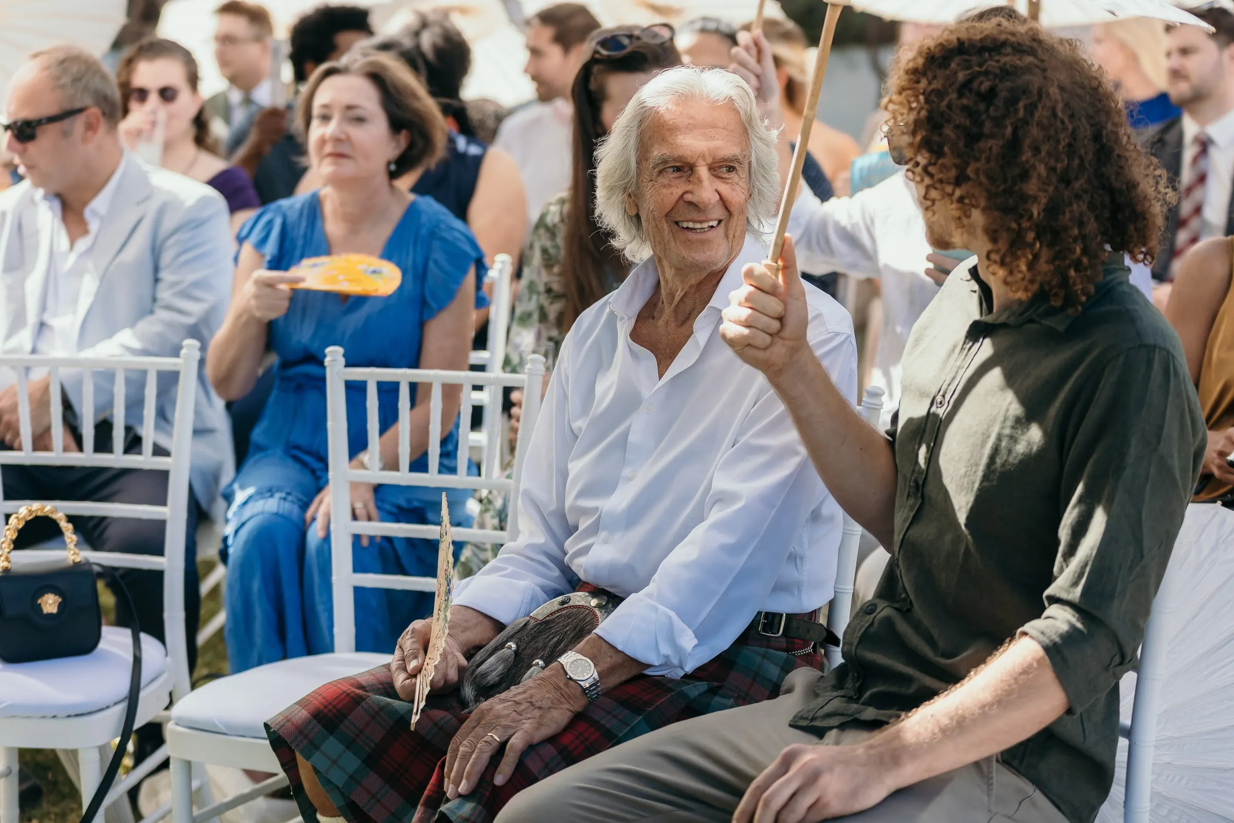 An older guest in a kilt smiling among the seated guests at the ceremony, Hacienda San José, Mijas