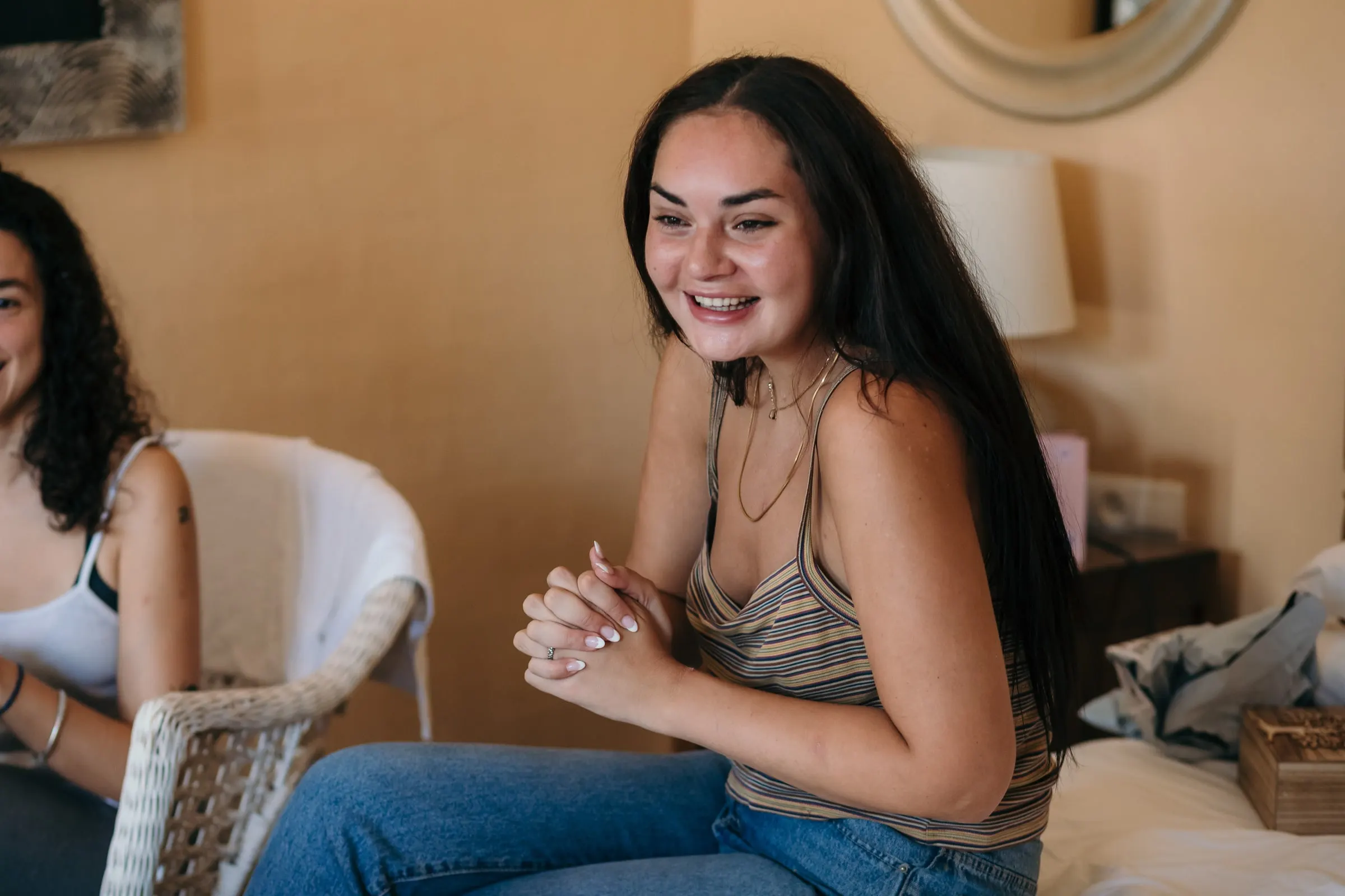 Smiling guest with long dark hair sitting in the getting-ready room before the wedding at Hacienda San José, Mijas