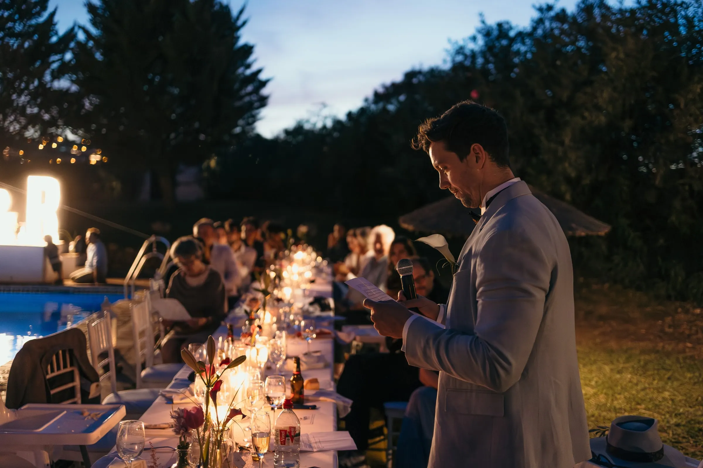 Guest in a grey suit reading a speech beside the long candlelit dinner table at Hacienda San José, Mijas