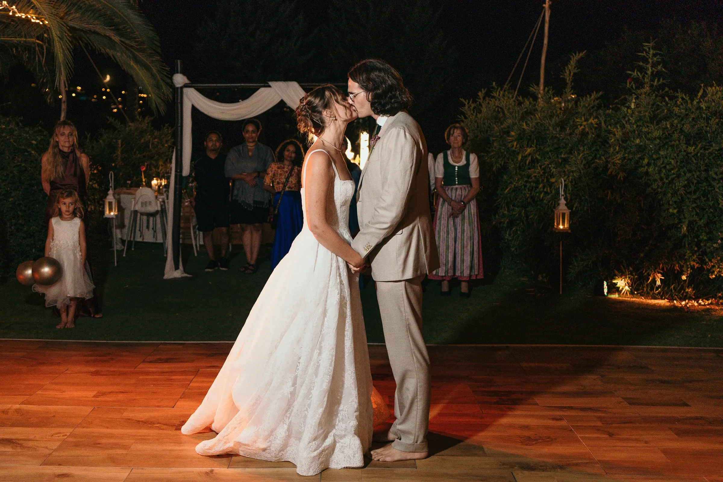 Bride and groom kissing on the dance floor at night, watched by guests, at Hacienda San José, Mijas