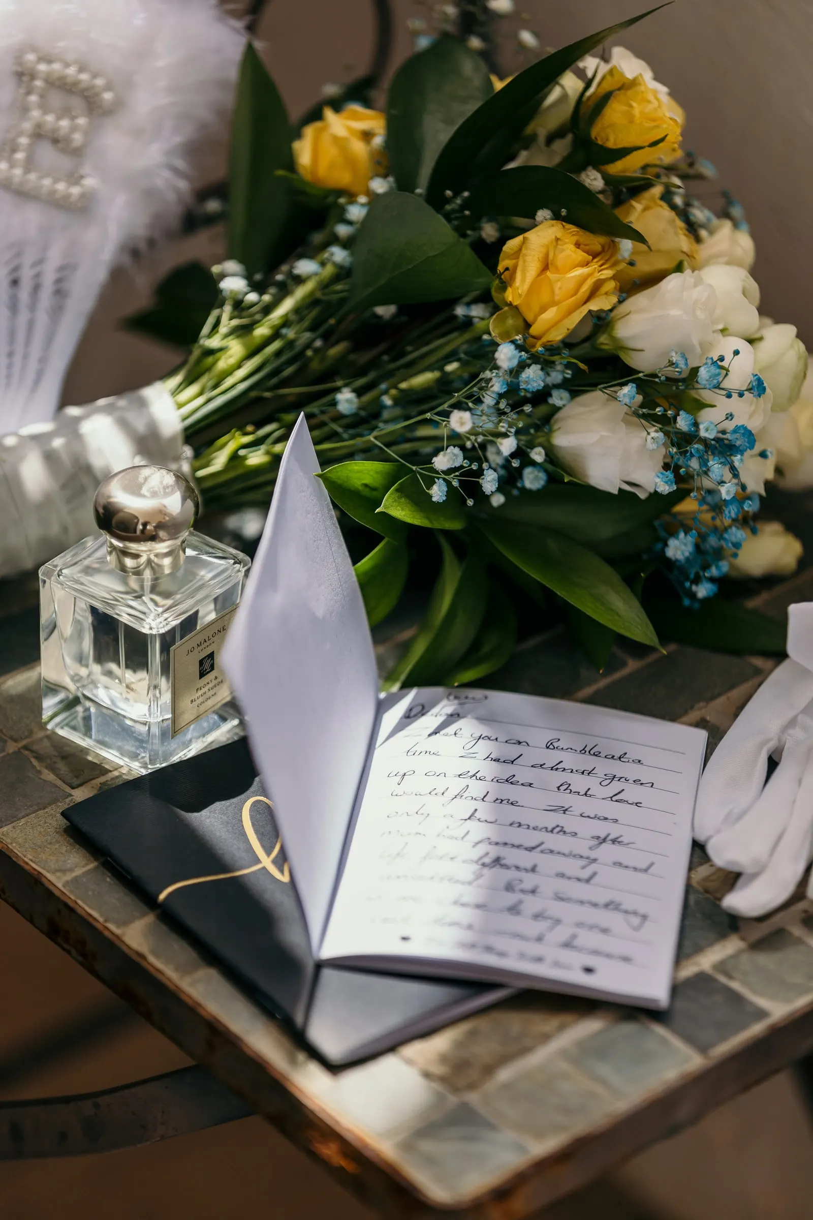 Yellow and white rose bouquet, perfume and a handwritten letter on a tiled table before the wedding in Mijas
