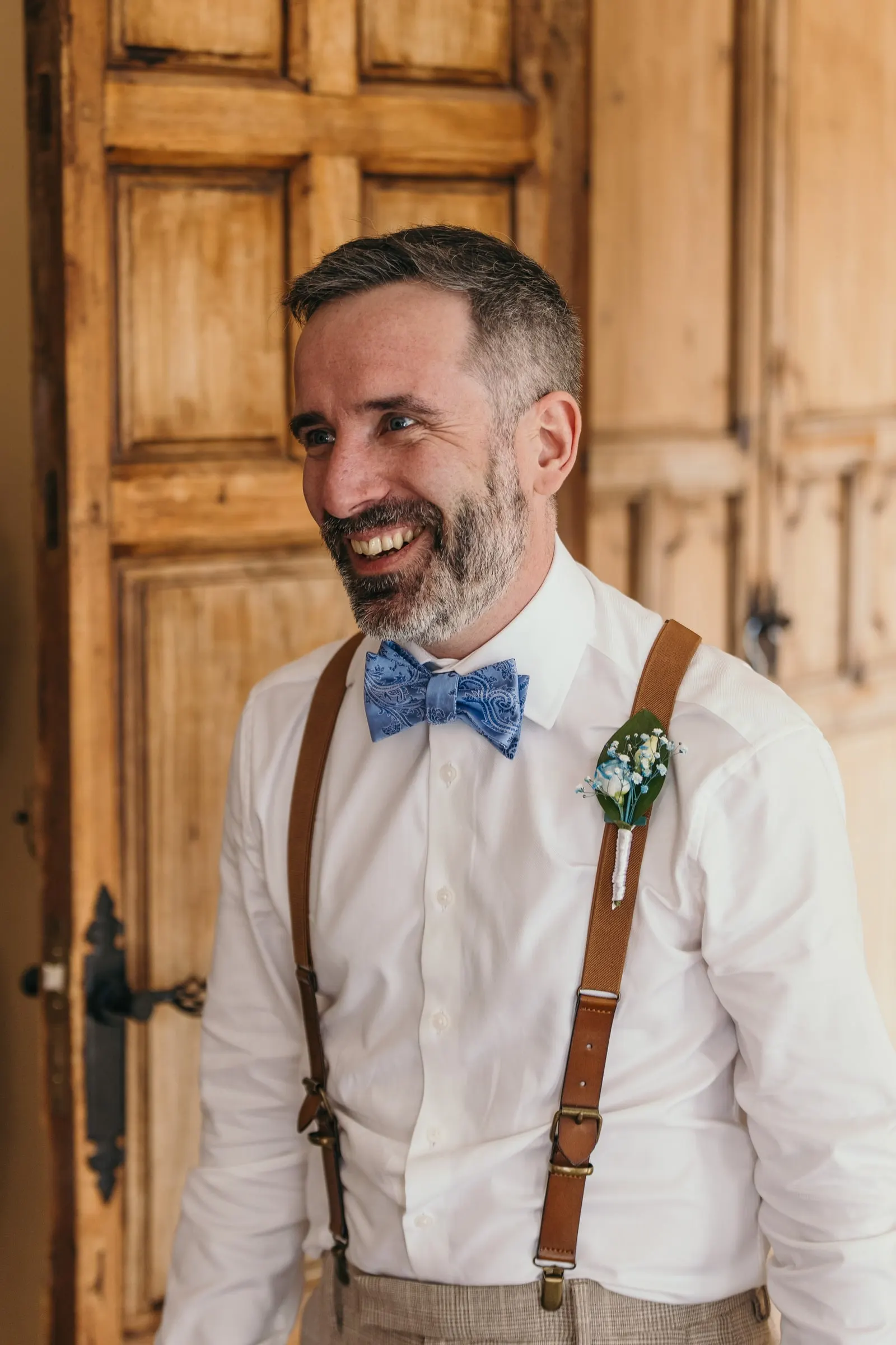 Man in braces and a blue bow tie beaming as he sees the bride ready, Mijas