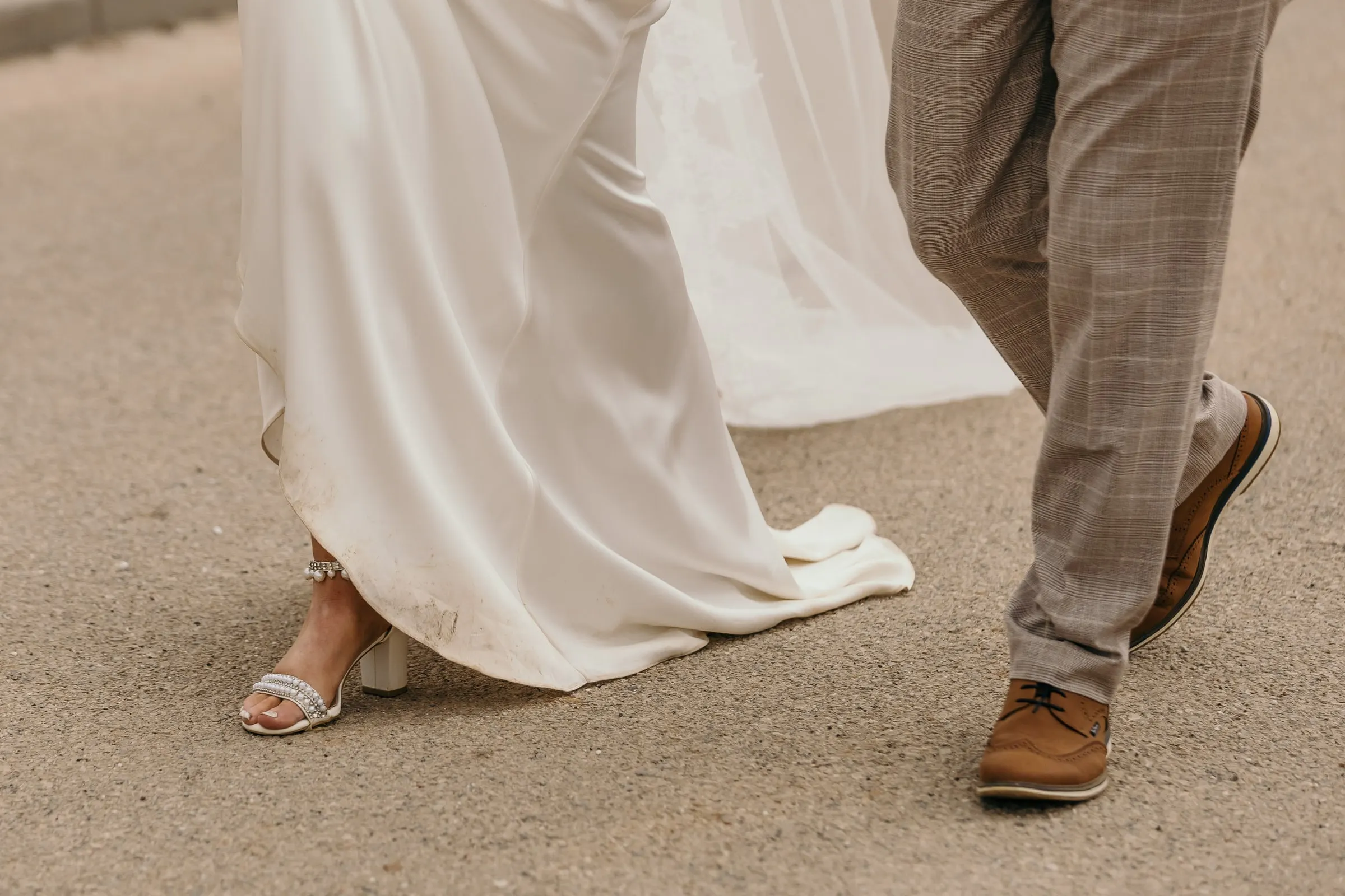 Detail of the bride's sandals and the groom's brown shoes walking on the road, Mijas