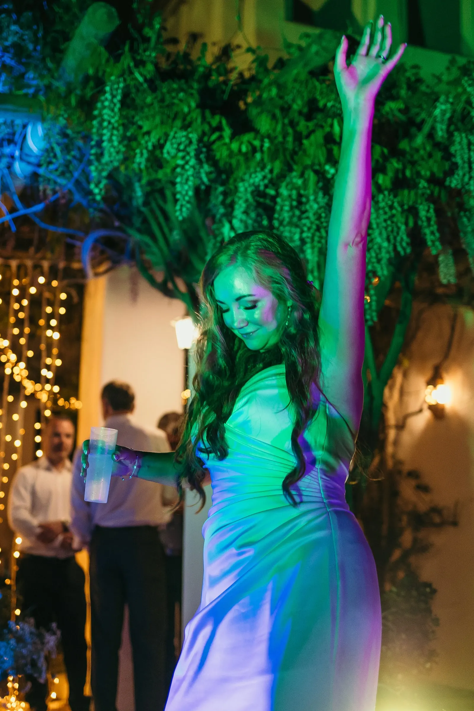 Bride in a green spotlight with her arm in the air on the dance floor at Hacienda San José