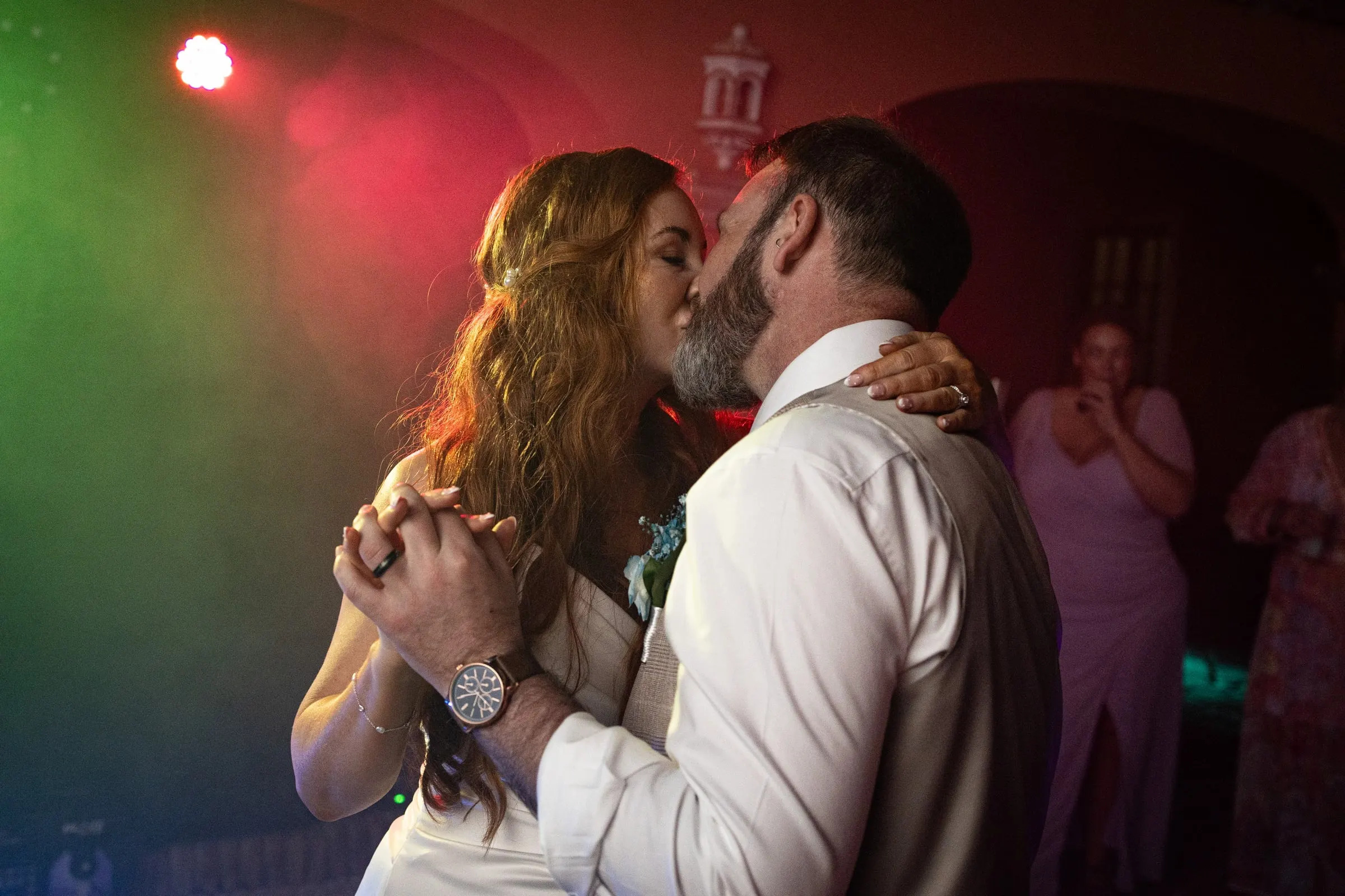 Couple kissing as they dance under red and green lights at Hacienda San José