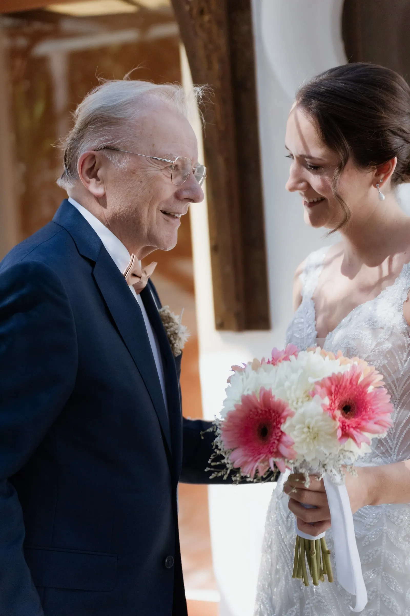 La novia se ríe con su familiar, con un ramo de gerberas rosas