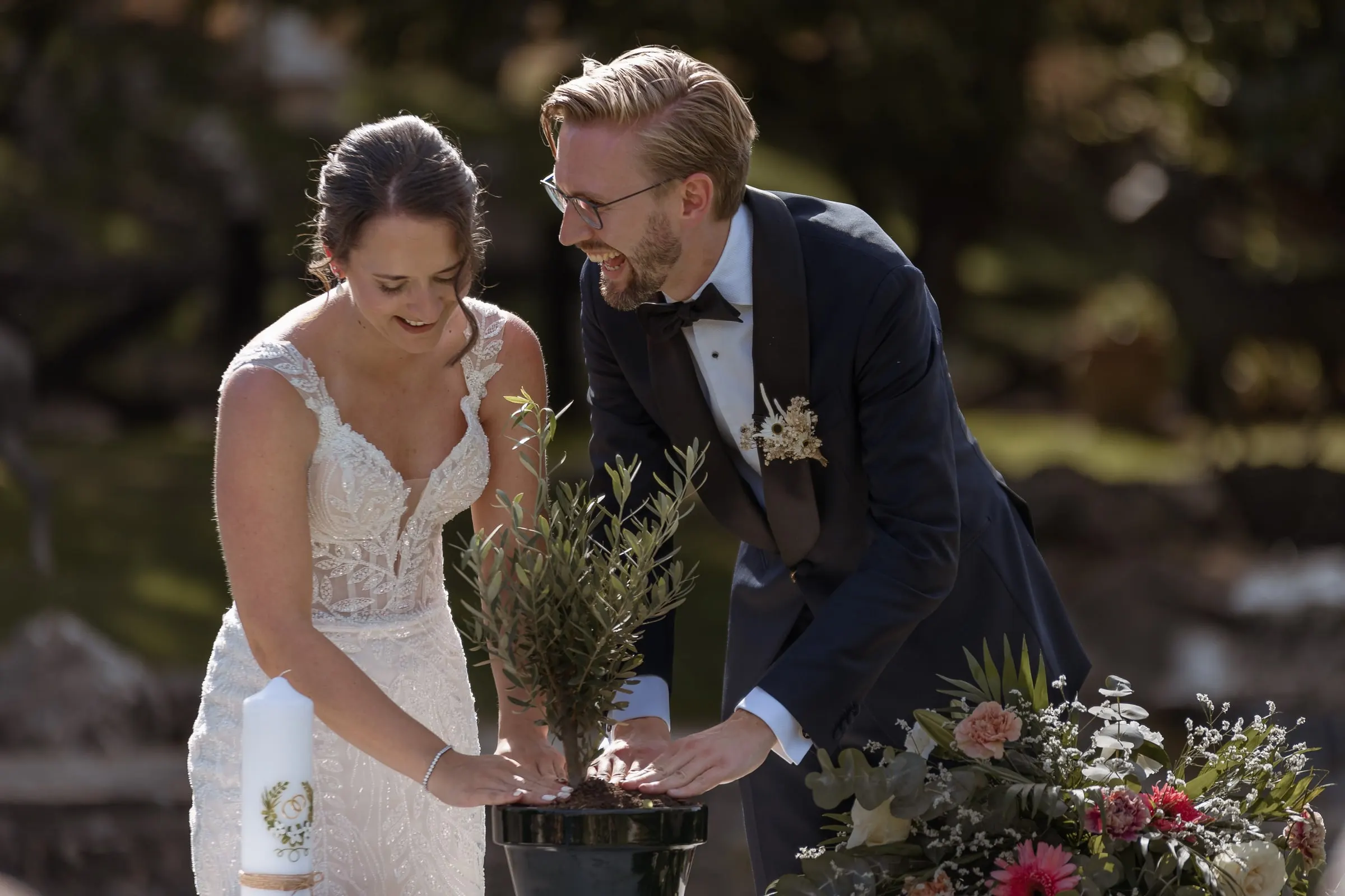 La pareja planta un pequeño árbol juntos durante la ceremonia al aire libre