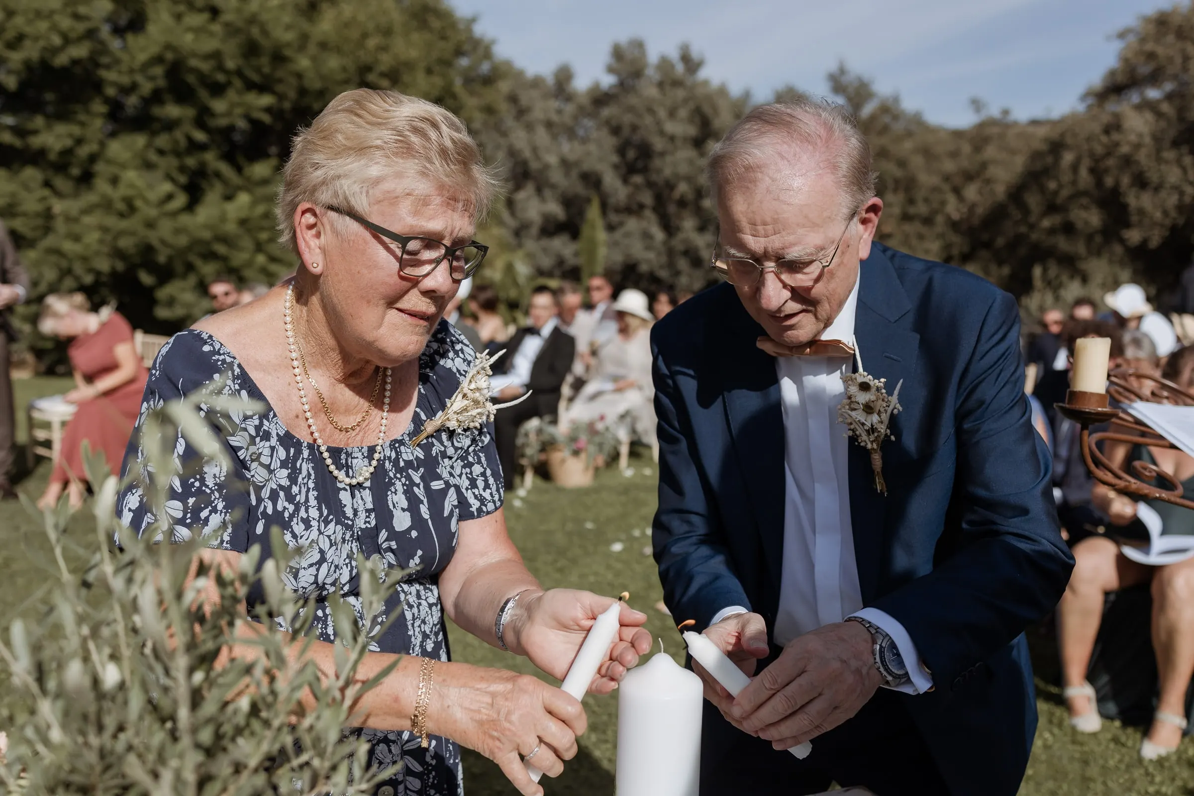 Una pareja mayor enciende una vela durante la ceremonia en el jardín