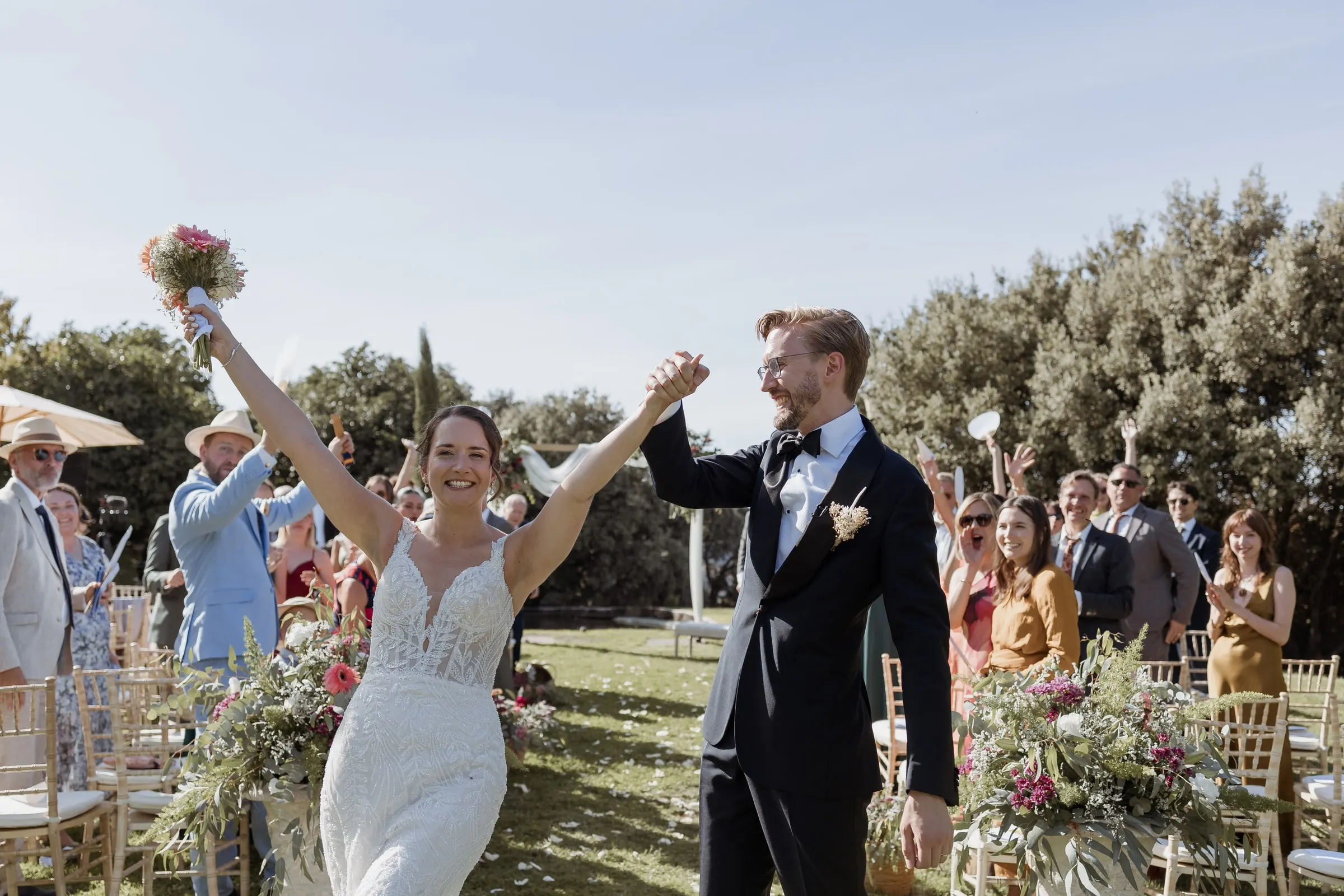 La novia levanta el ramo triunfante al final del pasillo