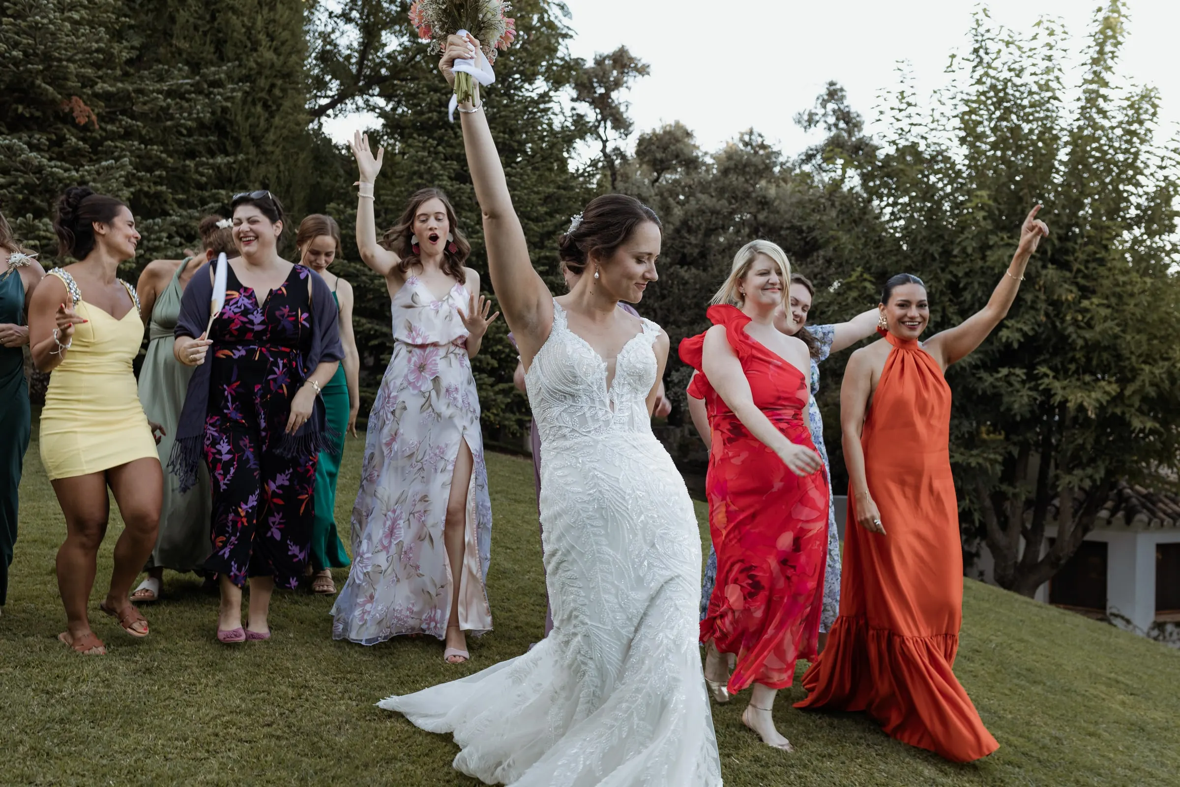 La novia baila en el césped con sus amigas de vestidos de colores