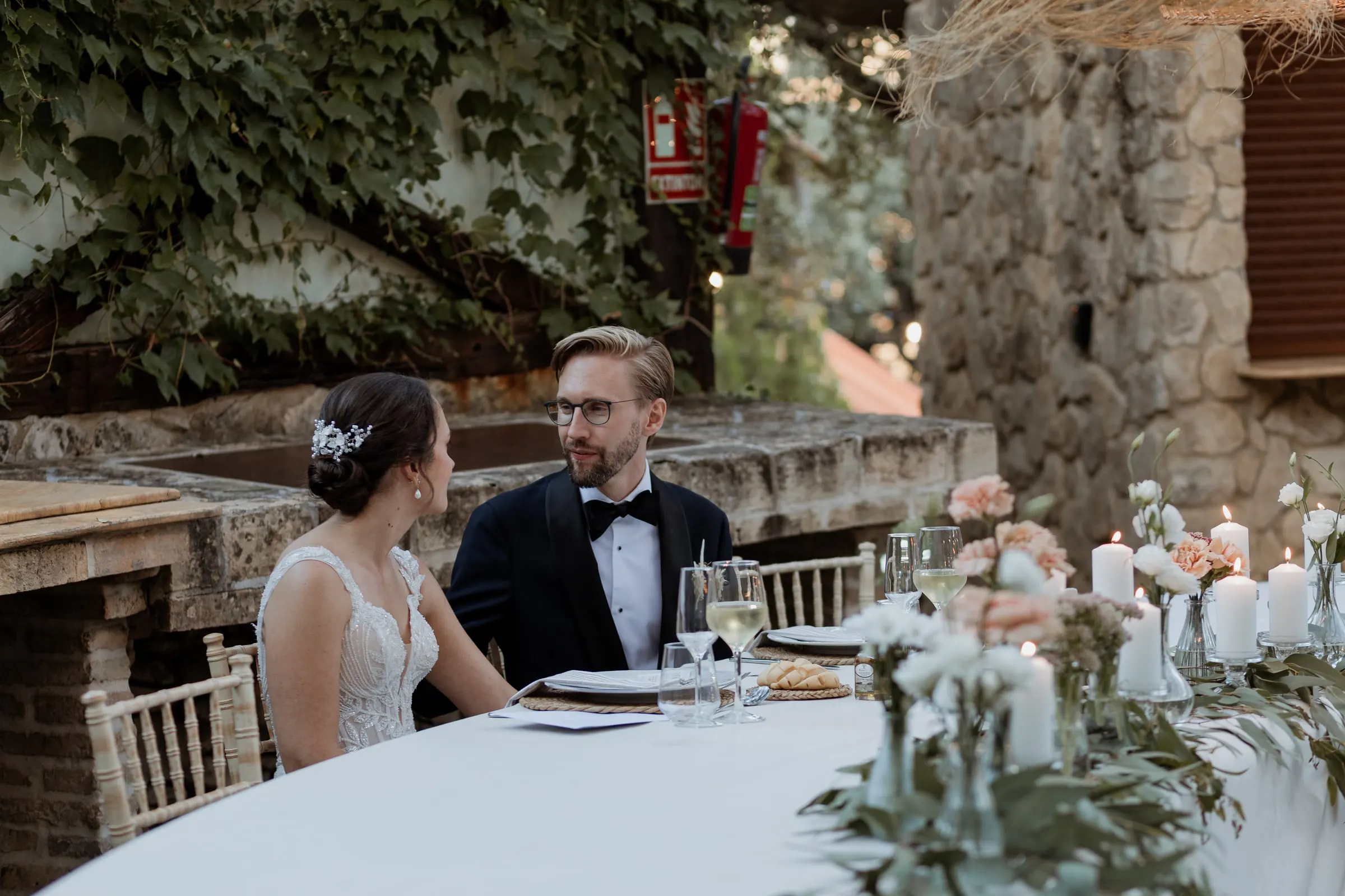 Bride and groom at their sweetheart table with candles and flowers