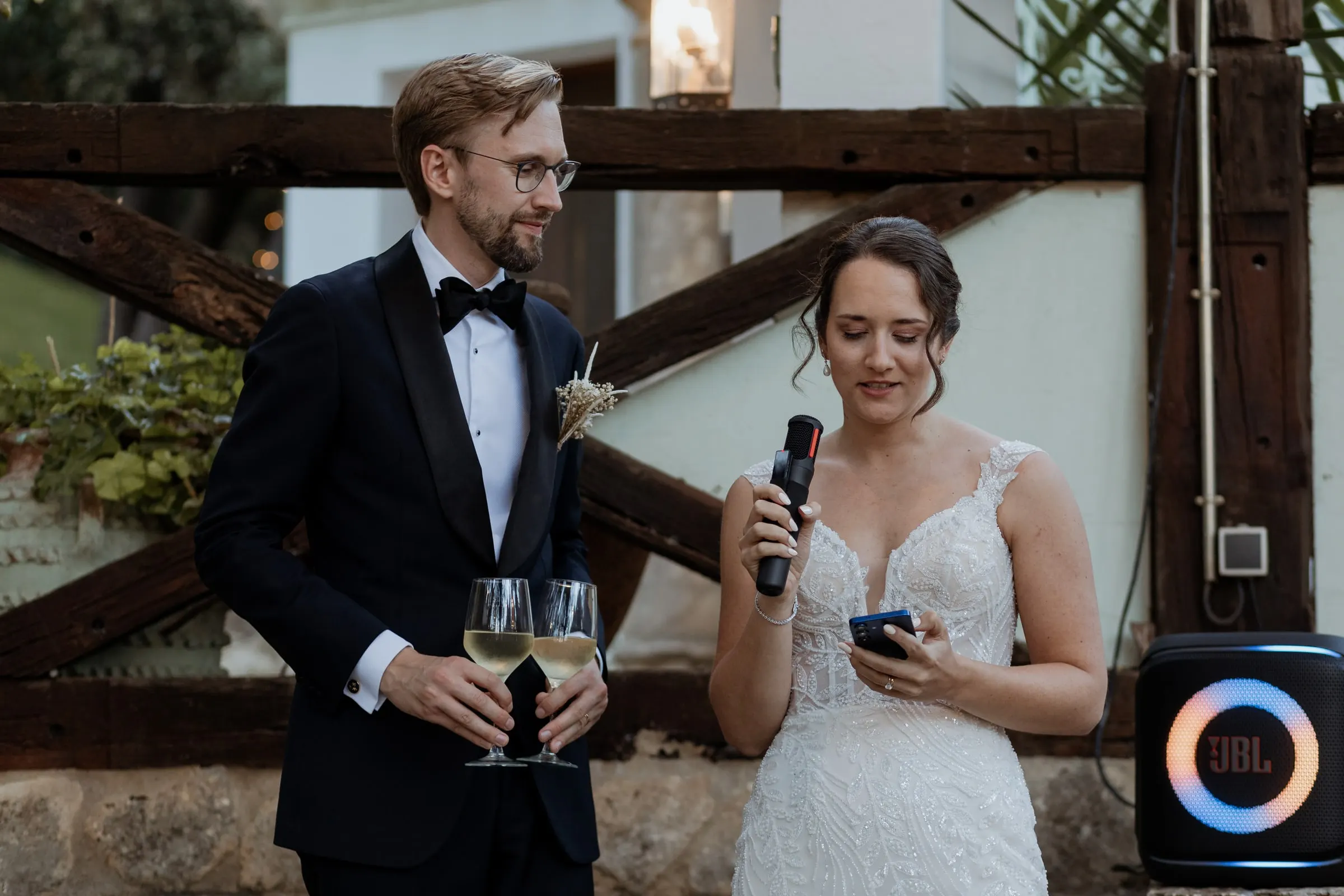 El novio da un discurso con el micrófono mientras la novia escucha