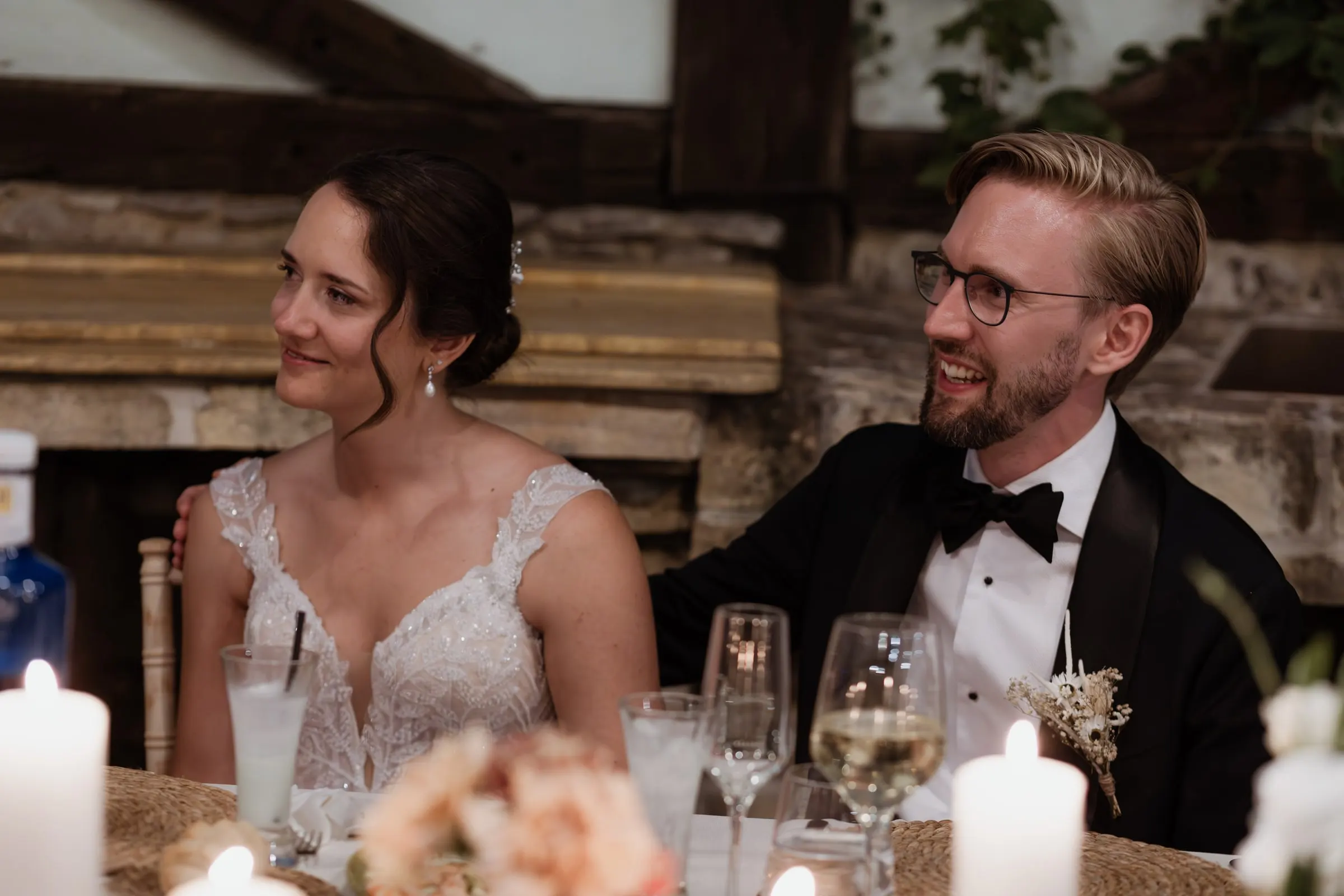 Los novios se ríen juntos en su mesa con velas