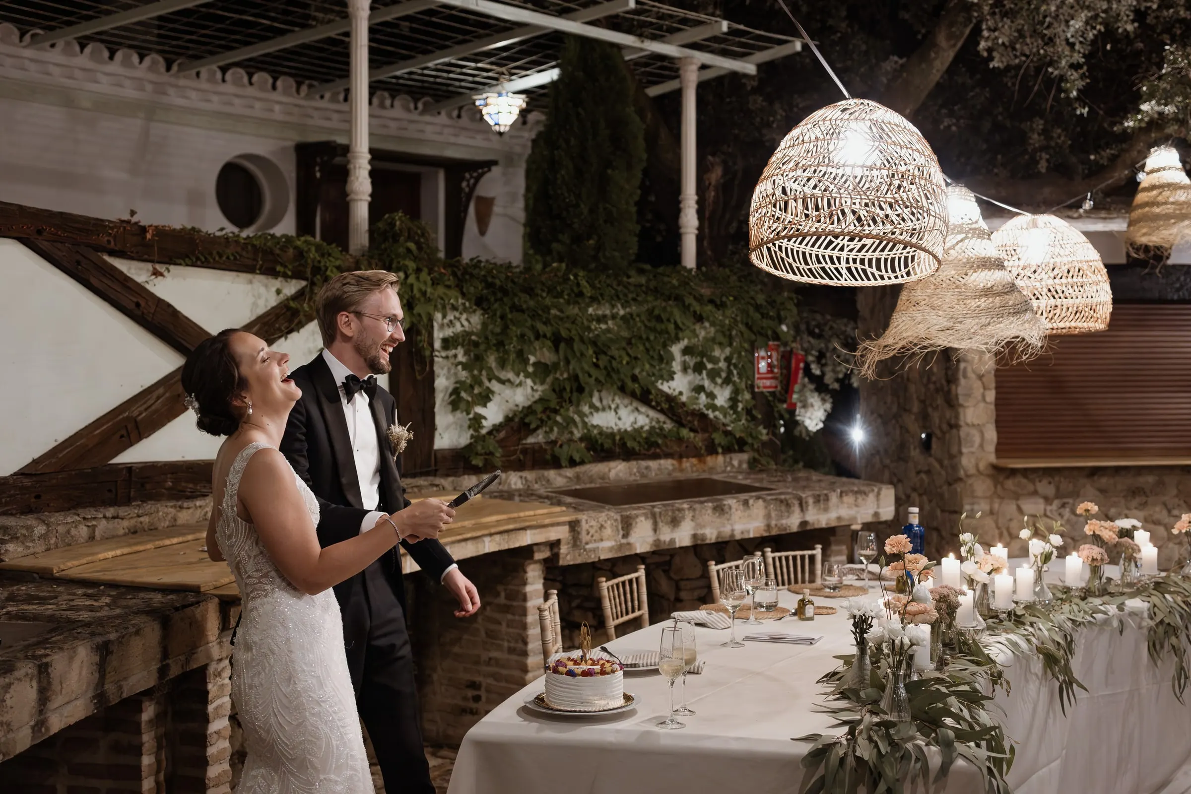 Los novios en la mesa de la tarta bajo lámparas de ratán en Ronda