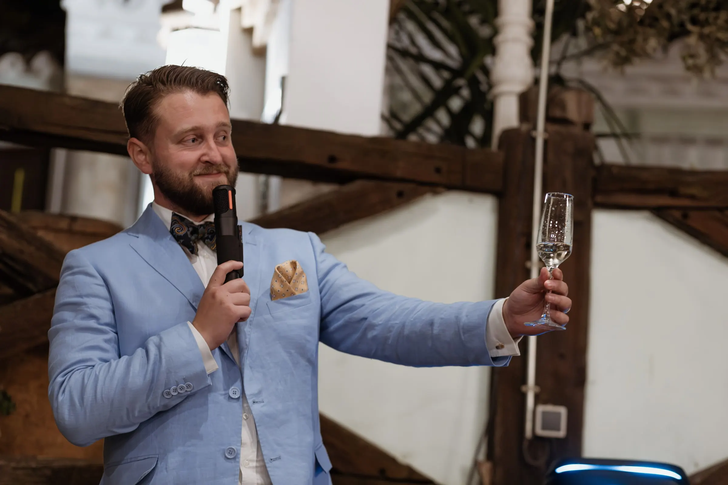 El padrino con chaqueta azul claro levanta su copa durante el discurso