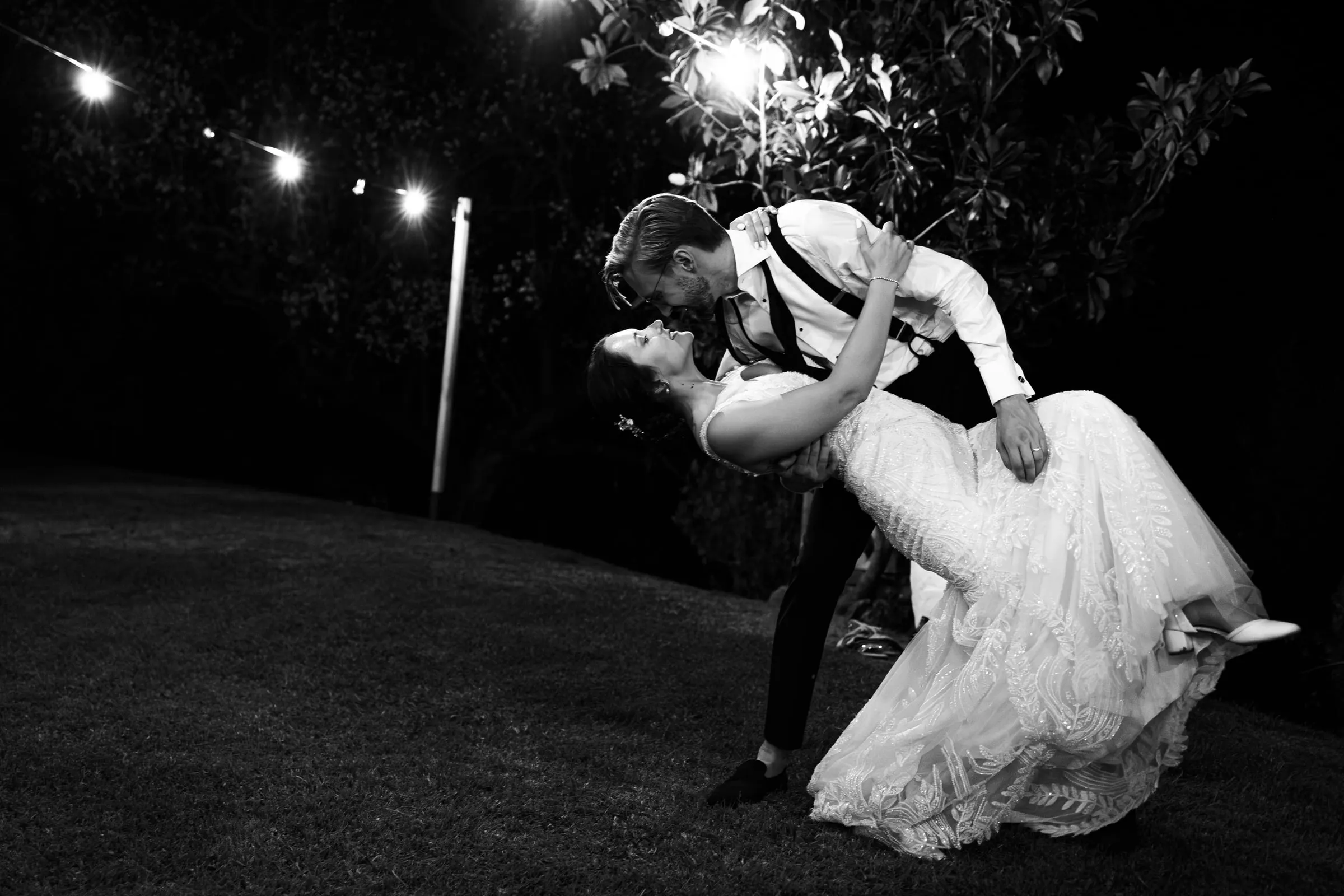 Beso inclinado en blanco y negro bajo las luces para cerrar la noche