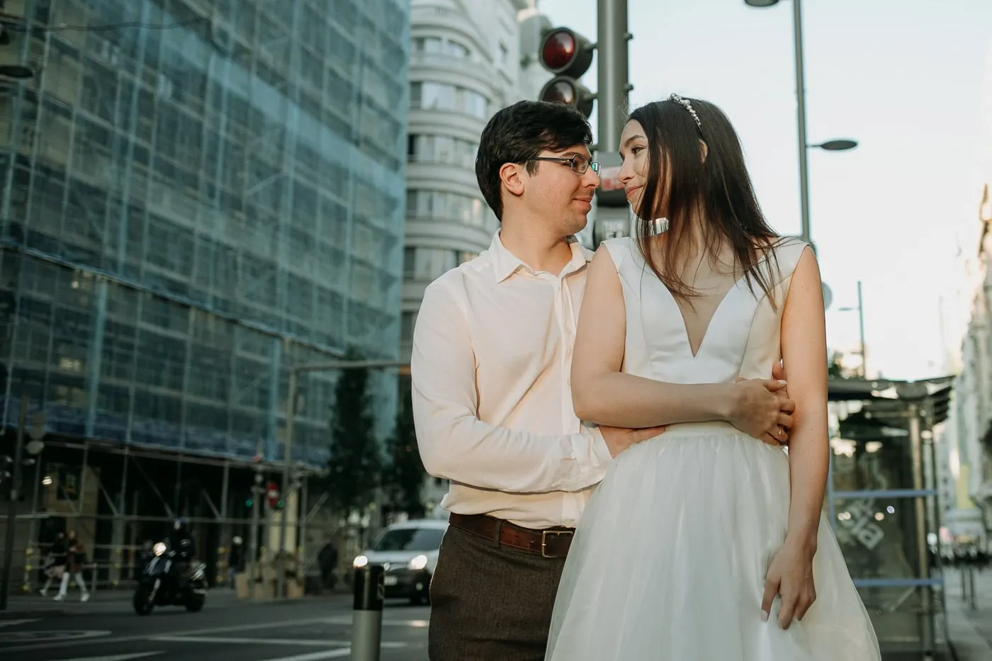 Los novios abrazados en una esquina con semáforos detrás