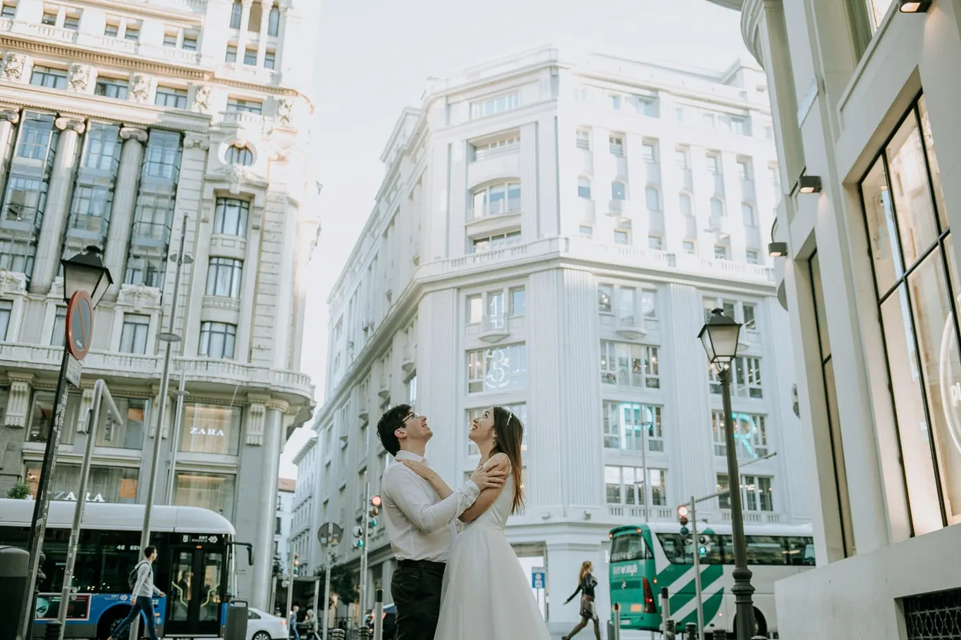 Los novios abrazados ante un edificio blanco de esquina en la Gran Vía