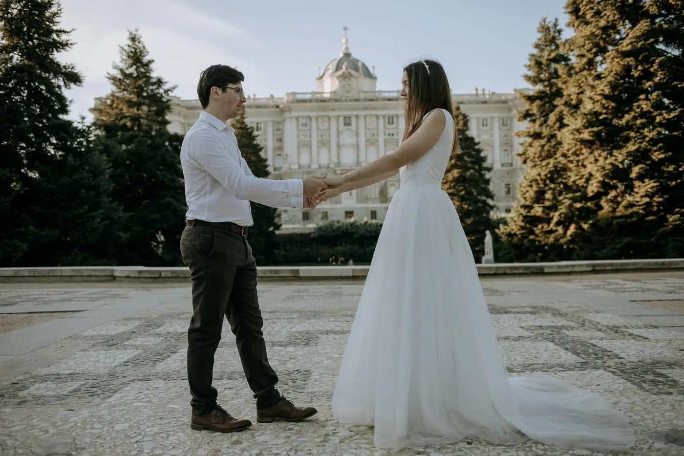 Los novios de la mano entre abetos frente al Palacio Real