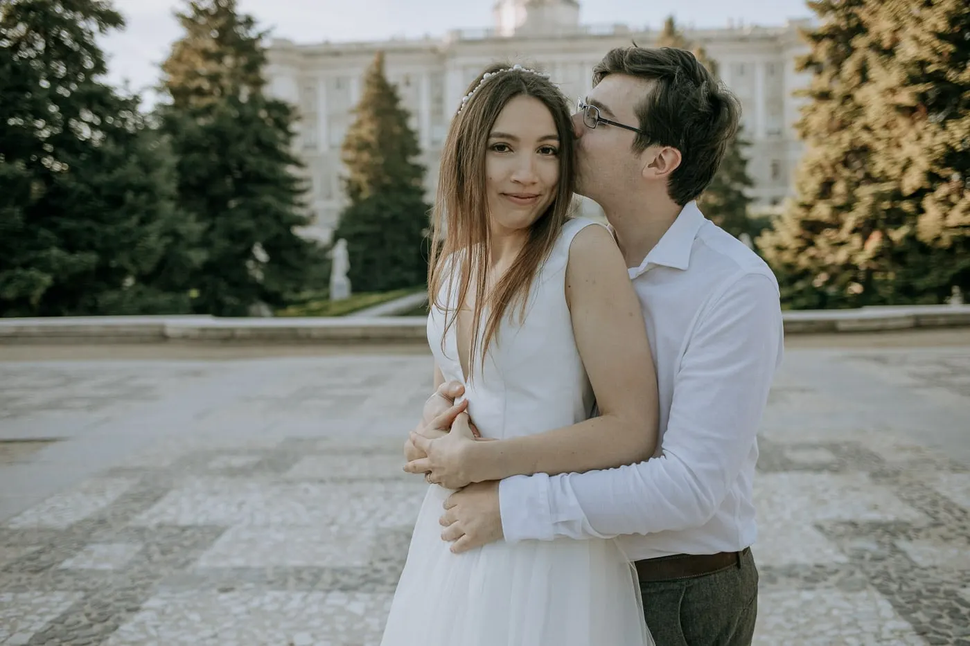 El novio besa la sien de la novia junto al Palacio Real, Madrid