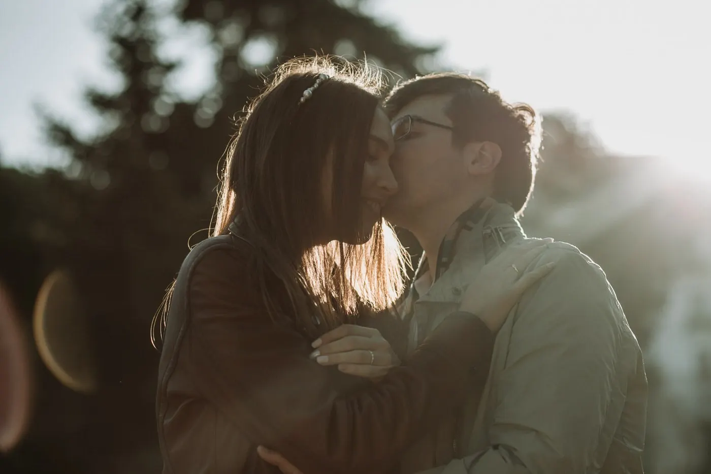 El novio besa la mejilla de la novia con el sol detrás
