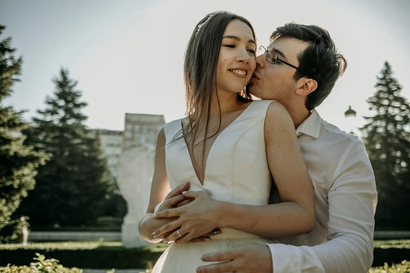 El novio besa por detrás a la novia sonriente