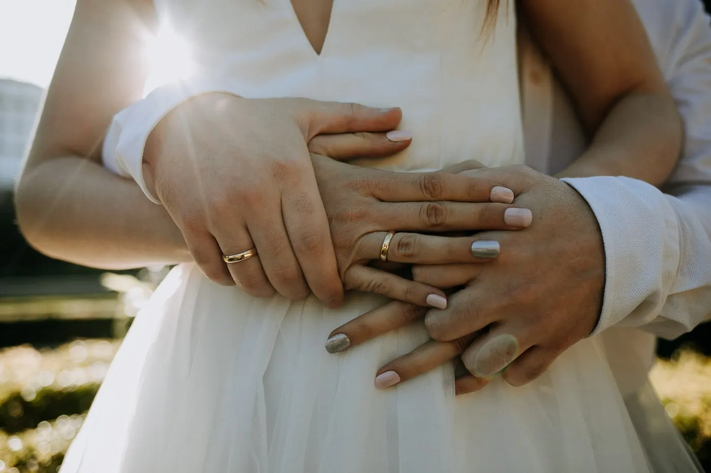 Detalle de sus manos y alianzas sobre el vestido de tul