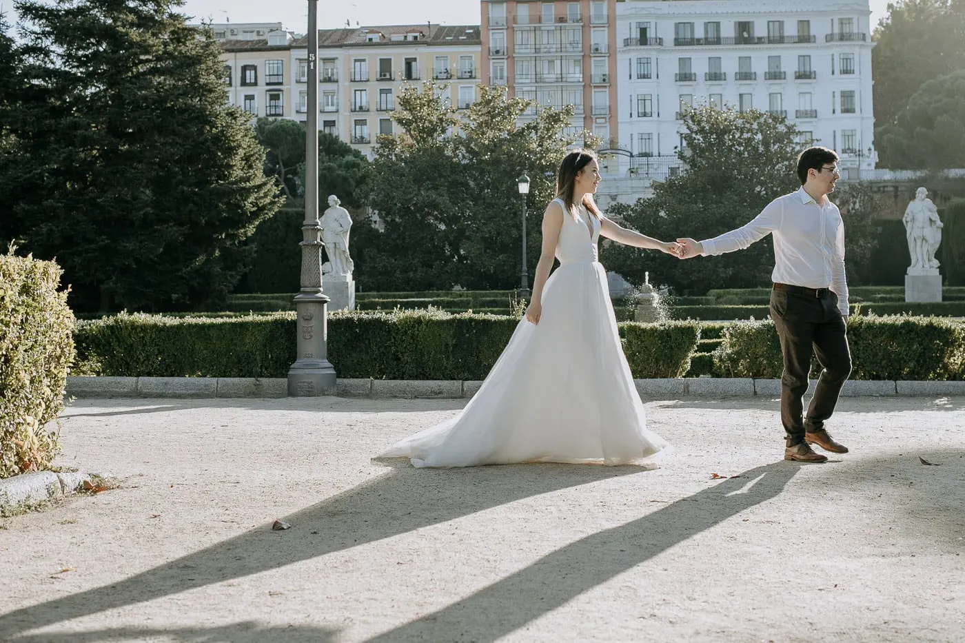 Los novios de la mano entre estatuas y setos junto al Palacio Real