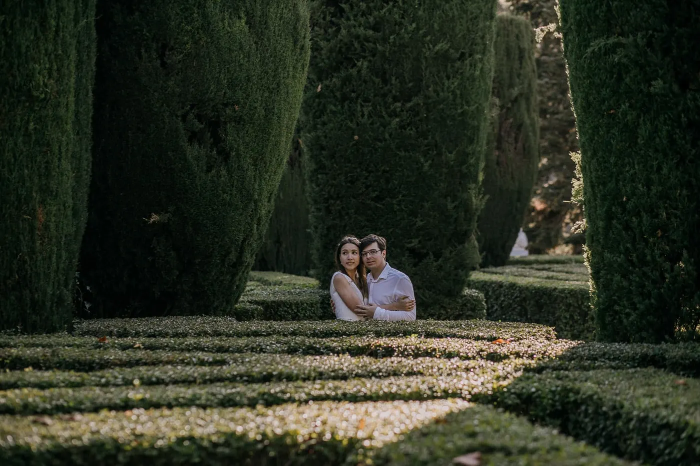 Los novios asoman entre los setos bajos del jardín