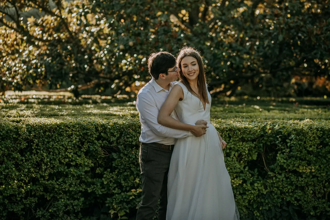 El novio besa la mejilla de la novia junto a un seto, Madrid