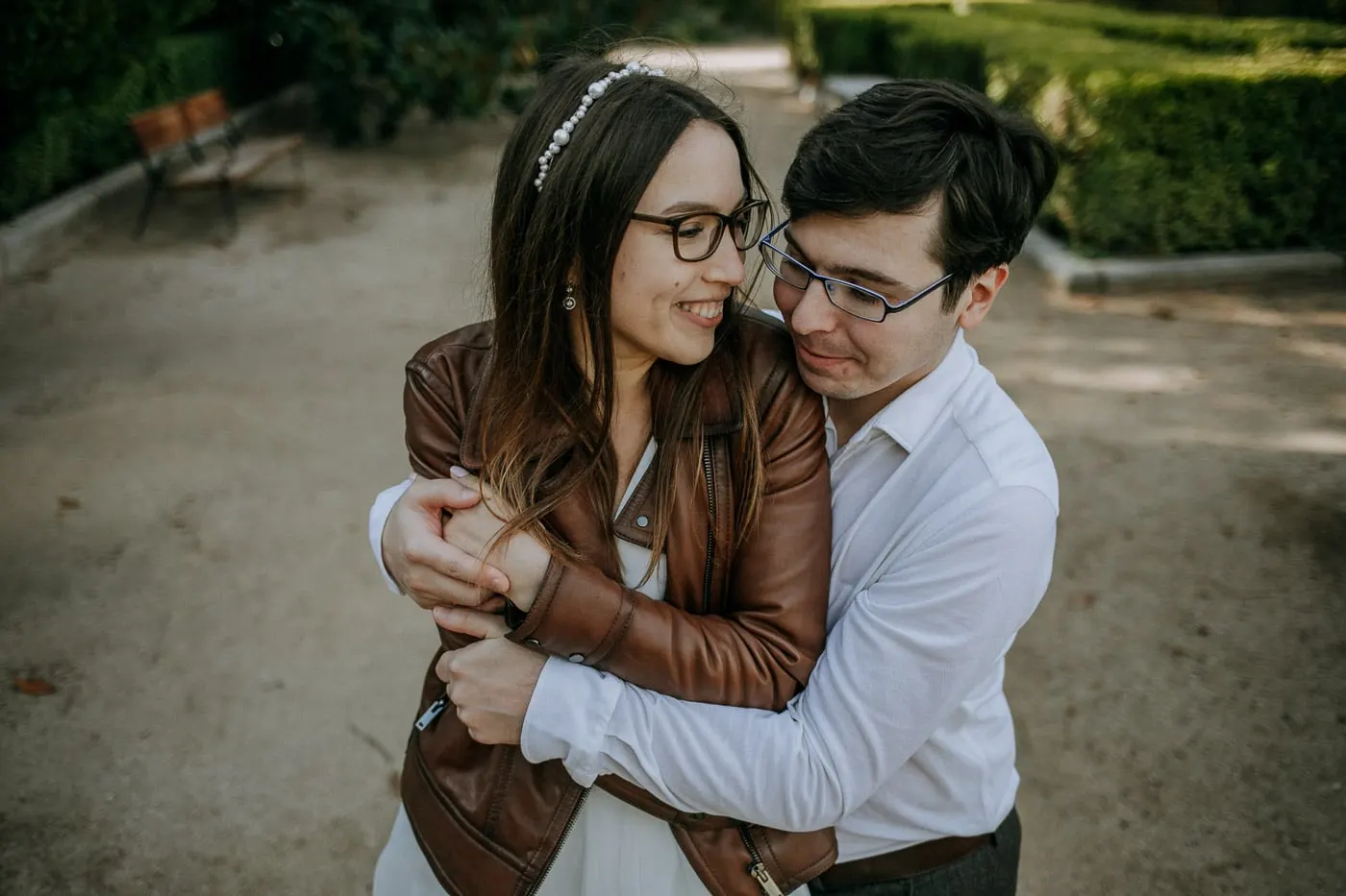 El novio abraza a la novia por detrás en un paseo del jardín