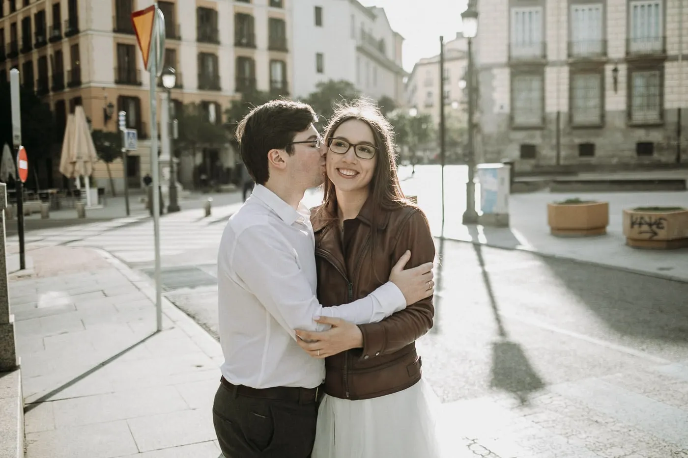 El novio besa la mejilla de la novia en una esquina soleada