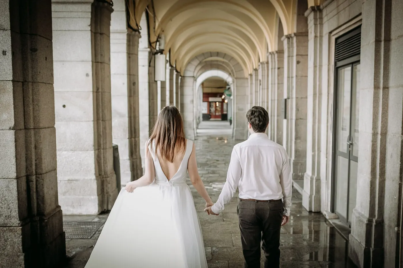 Los novios caminan de la mano bajo los soportales de la Plaza Mayor, Madrid