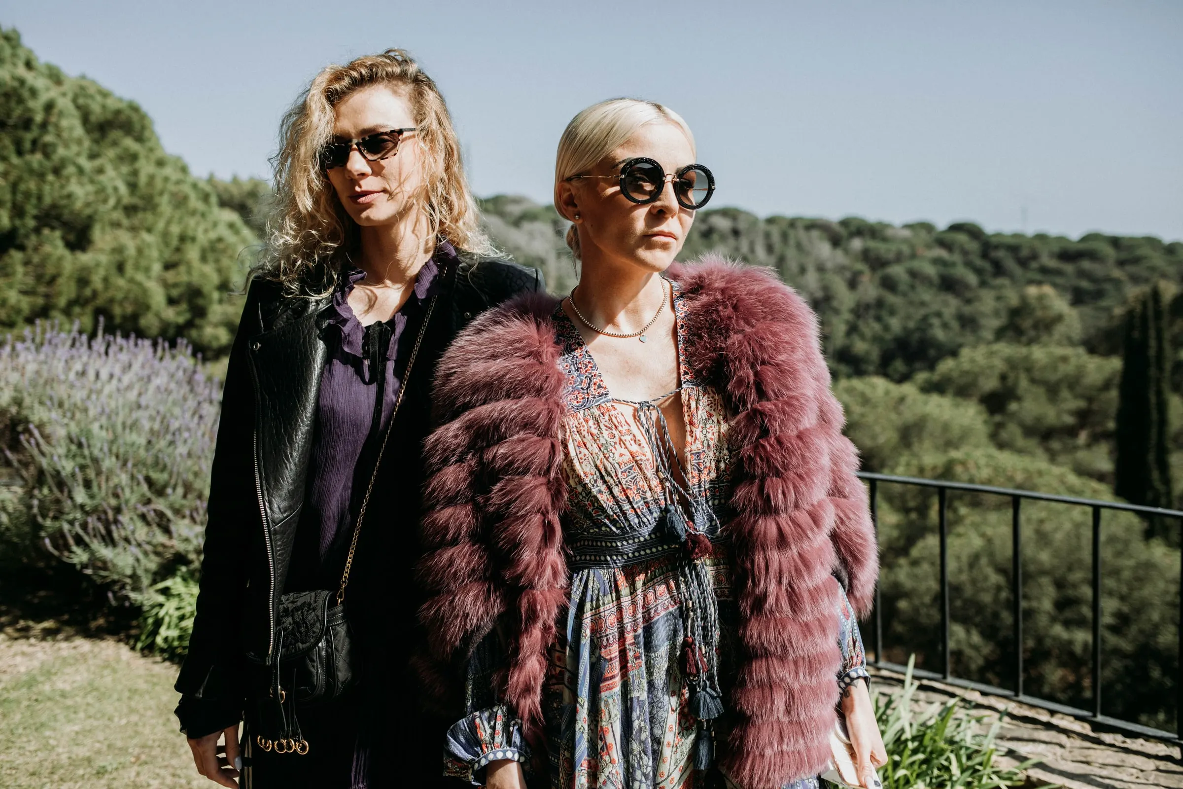 Dos invitadas con gafas de sol, una con chaqueta de pelo granate, en la terraza de una masía de Girona