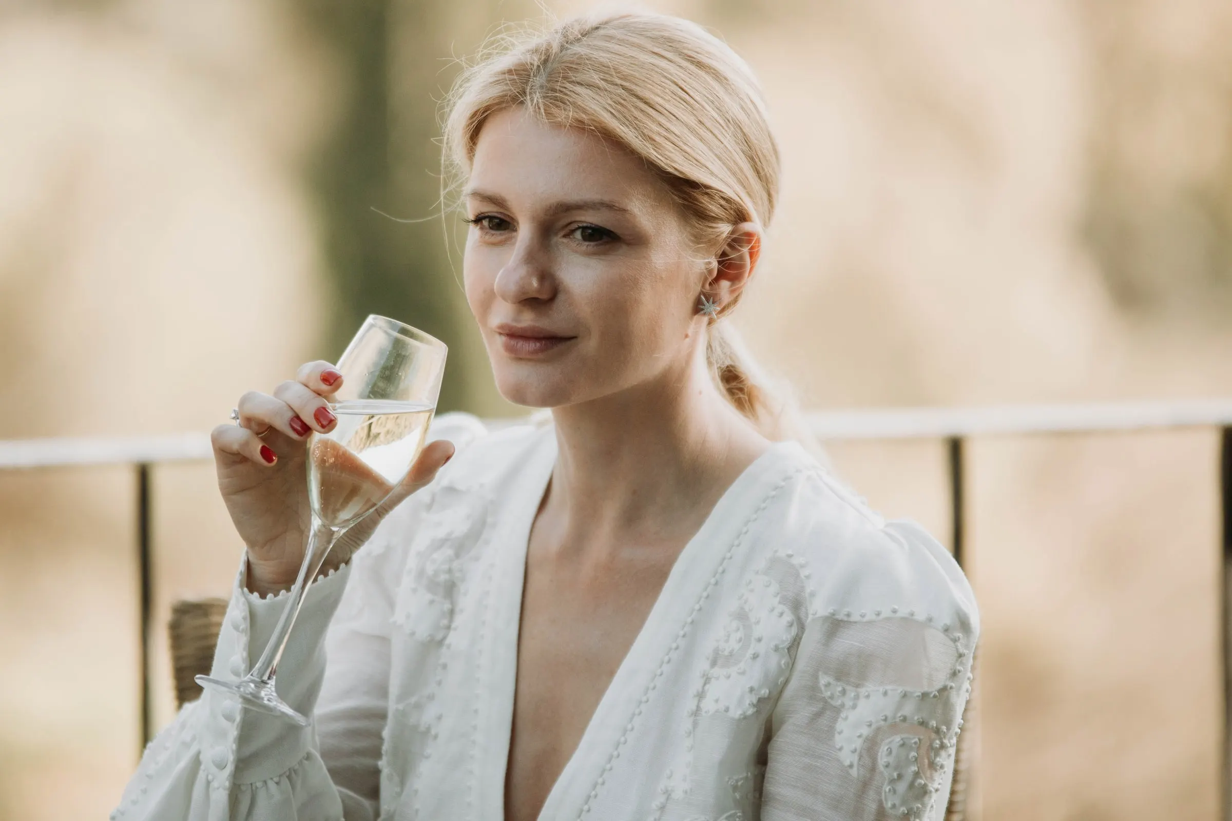 La novia, con una copa de cava en la mano, mira hacia un lado en la terraza de una masía de Girona