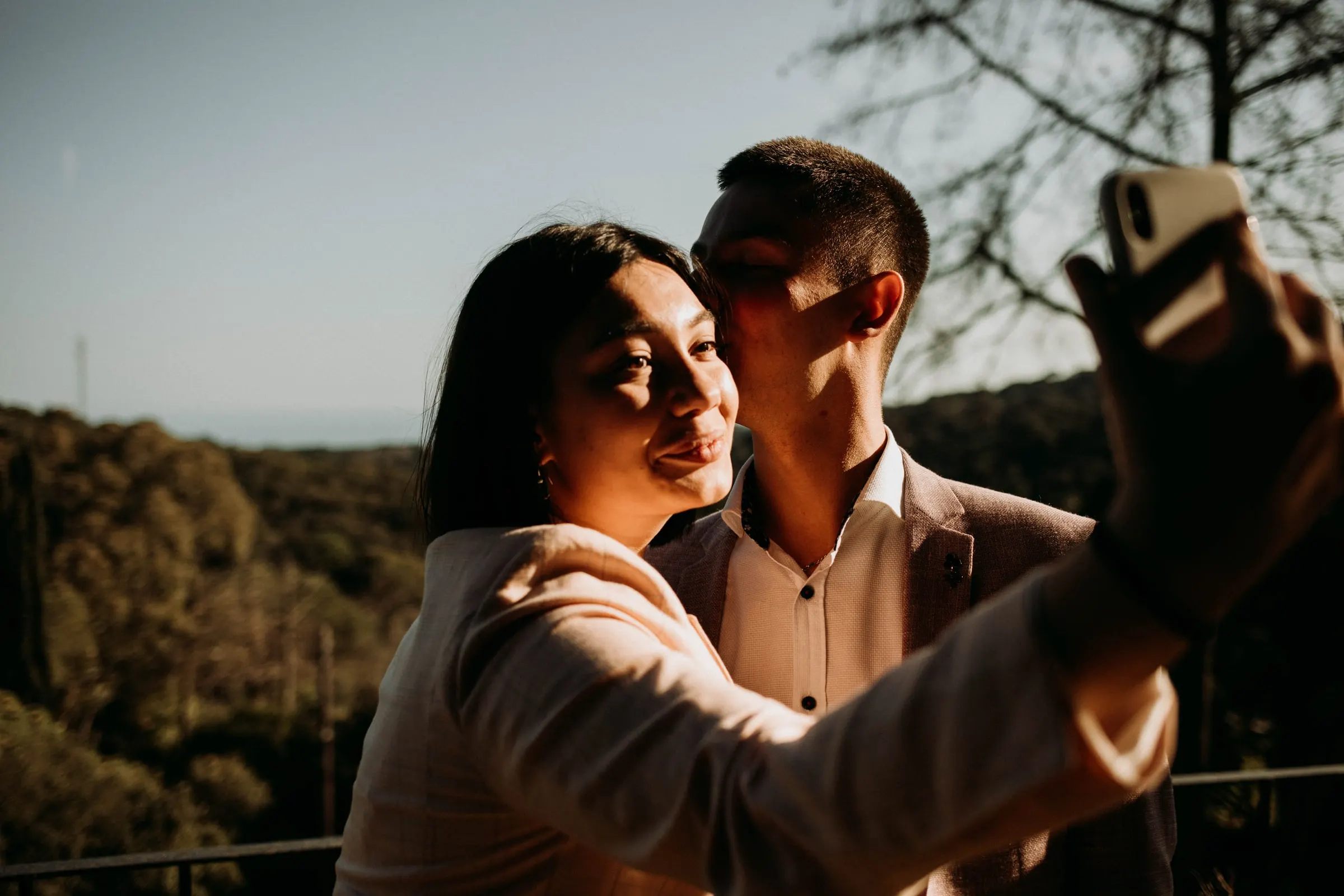 Dos invitados se hacen un selfie al atardecer frente a las colinas boscosas de una masía de Girona
