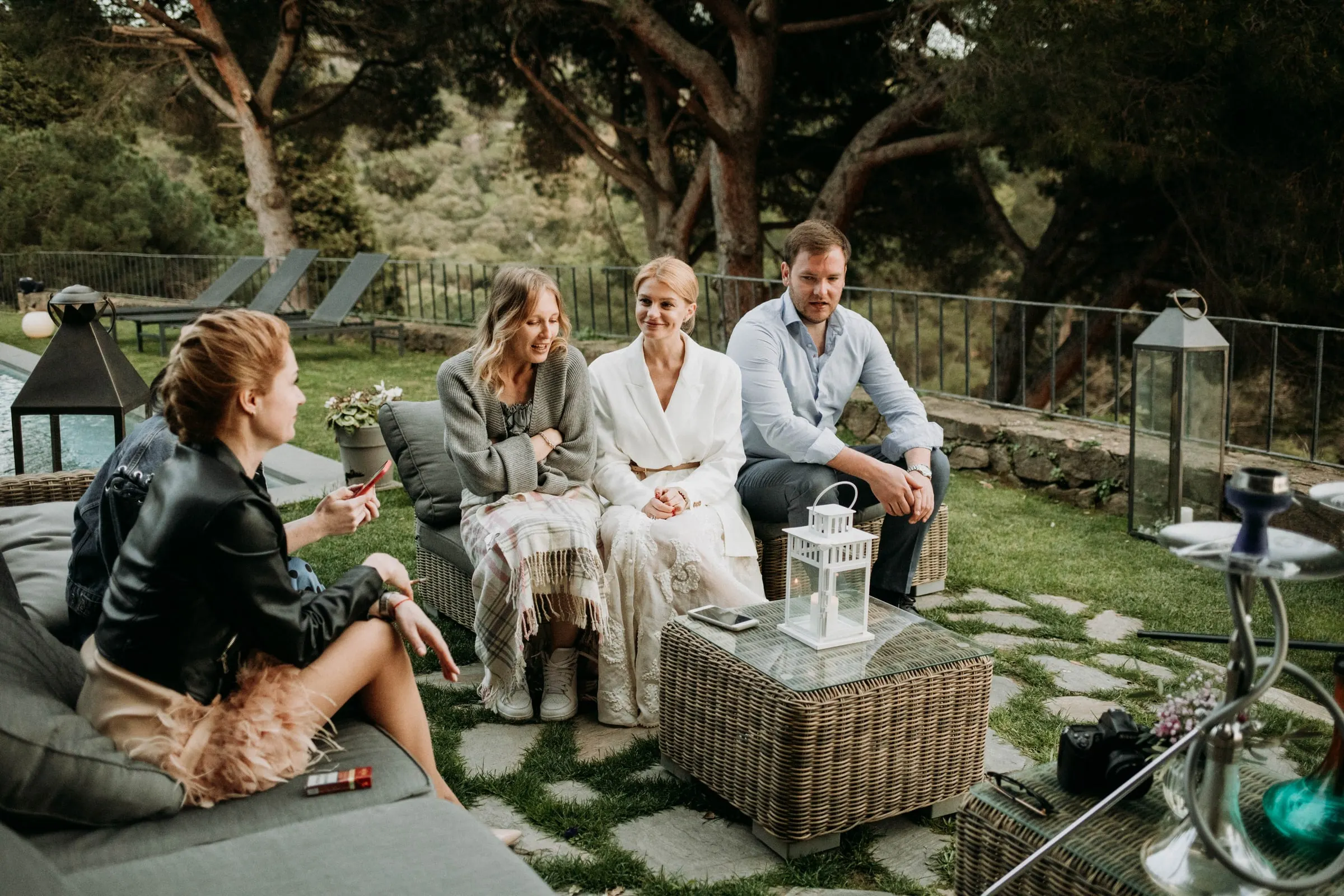 La novia charla con amigos en sofás de mimbre en el jardín de una masía de Girona