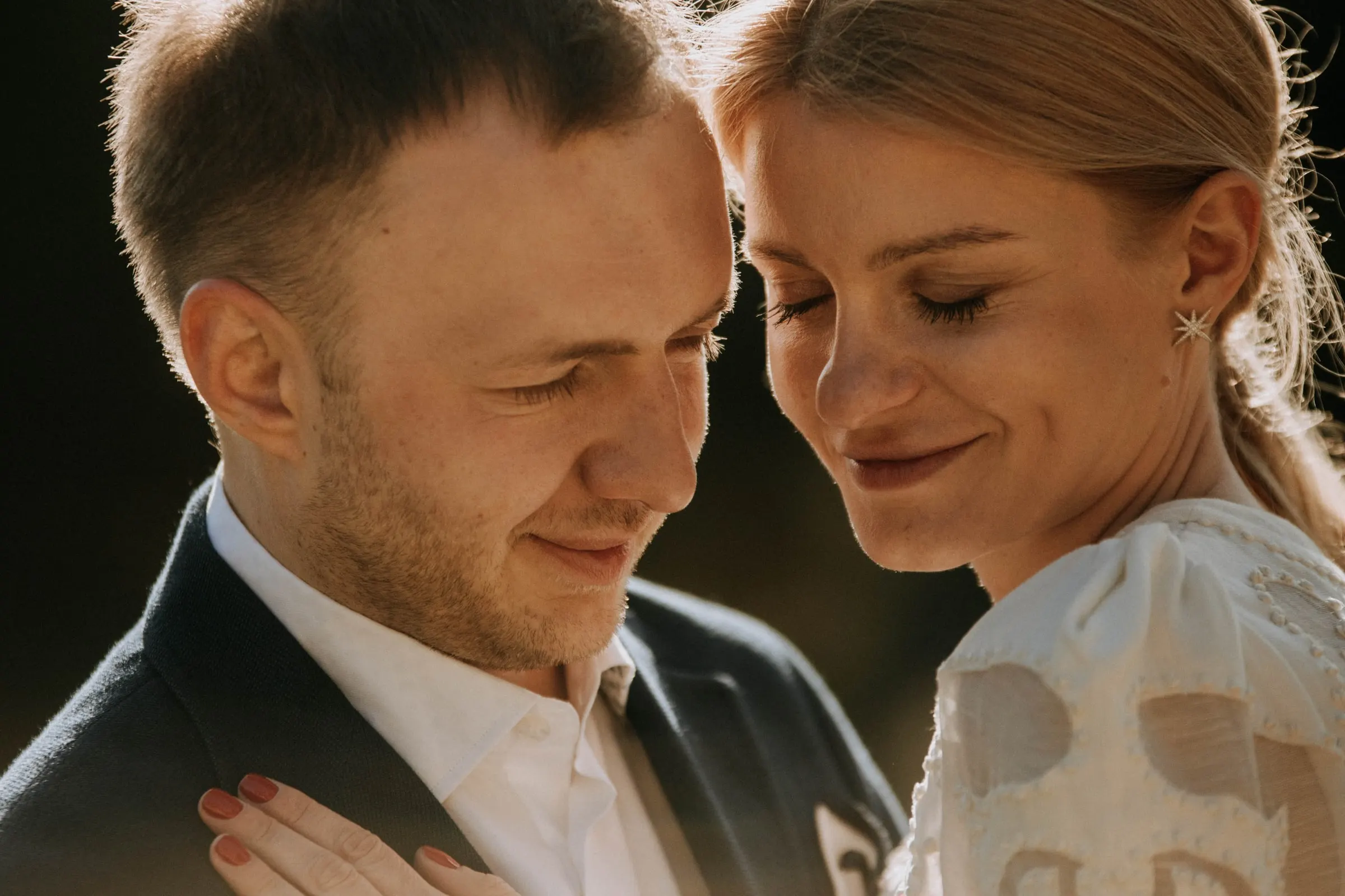 Primer plano de los novios mejilla con mejilla y los ojos cerrados, con luz cálida, en una masía de Girona