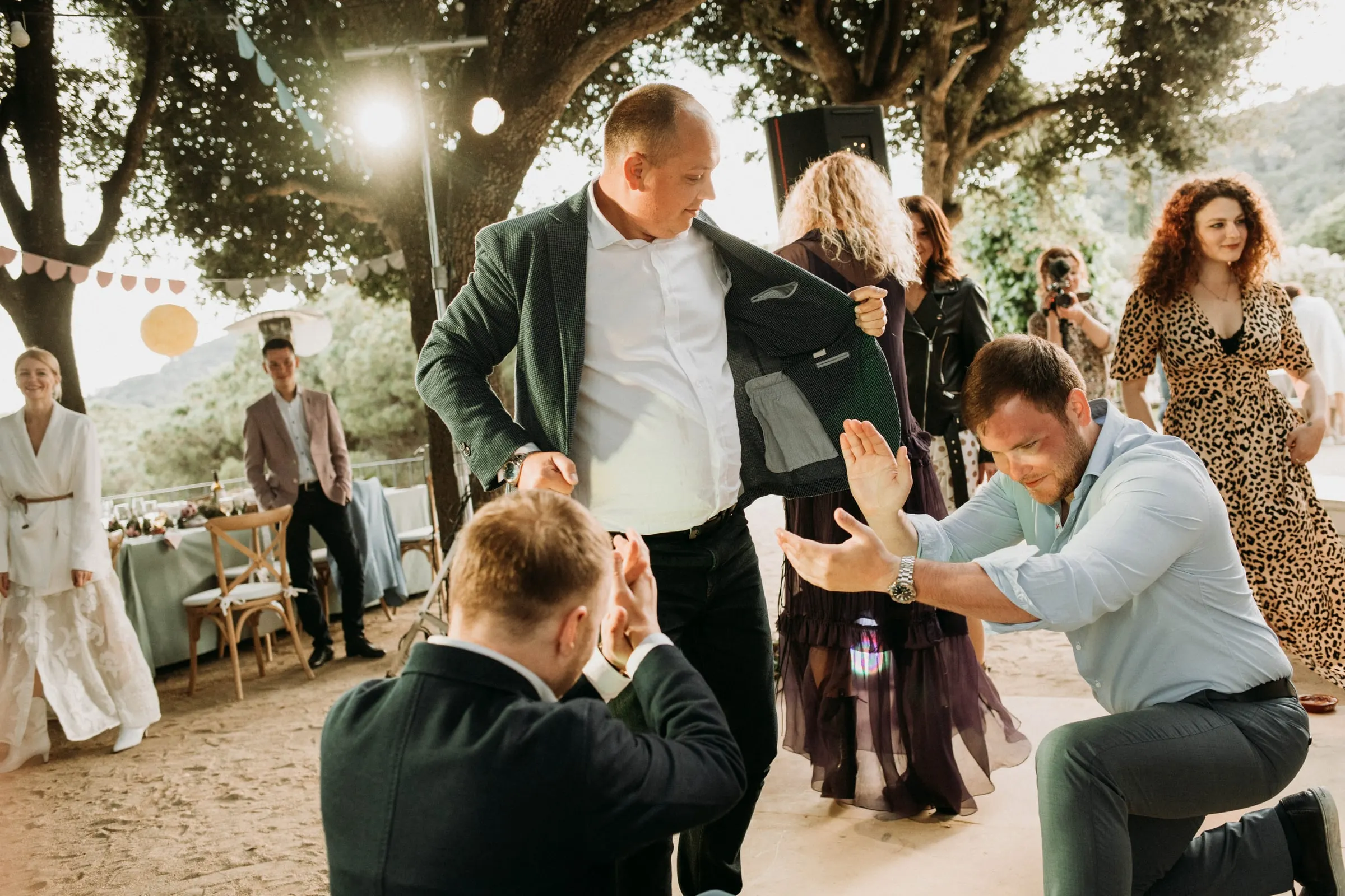 Invitados bailan y se arrodillan en corro en la pista al aire libre de una masía de Girona