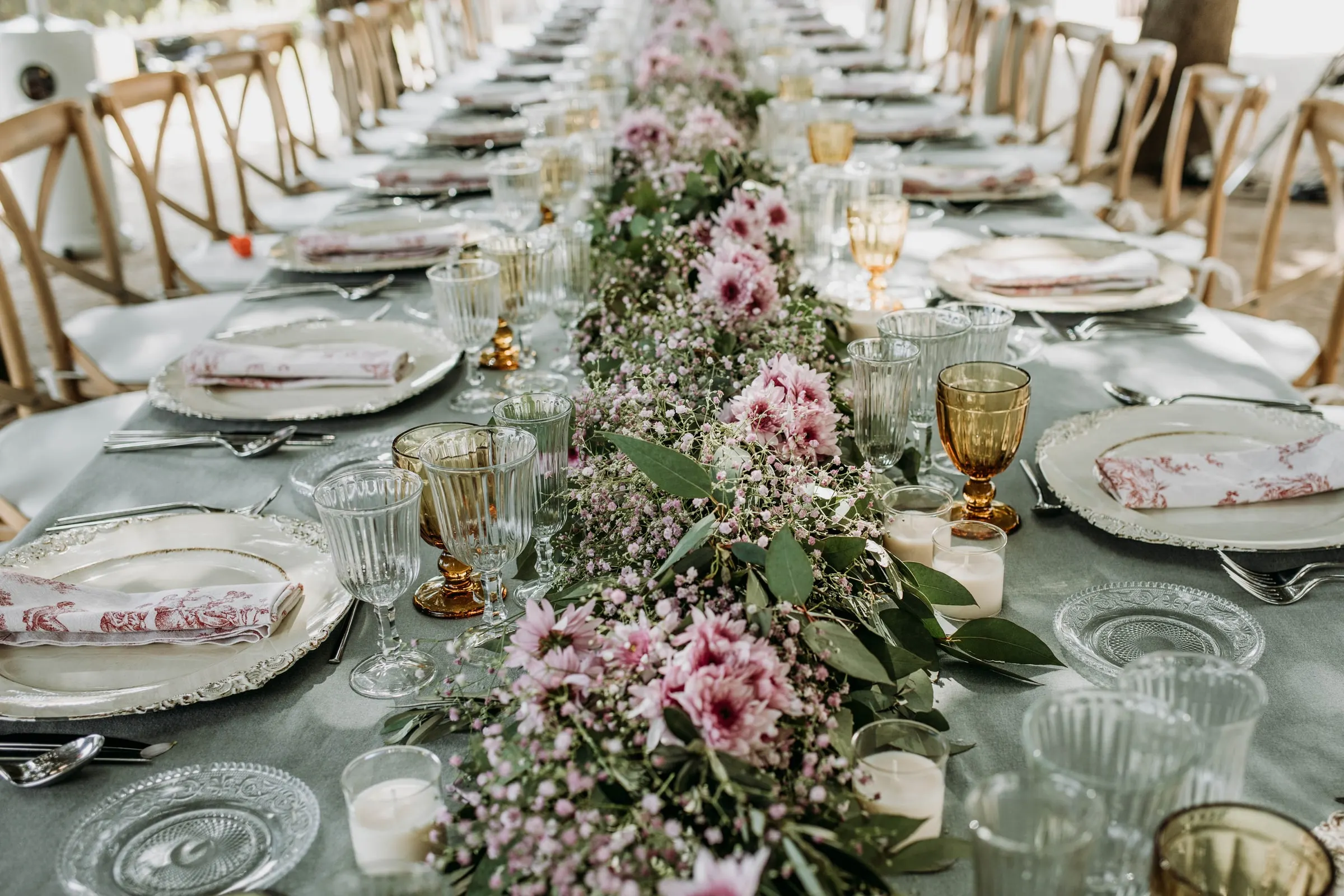 La mesa larga del banquete, con flores rosas y copas ámbar, en una masía de Girona