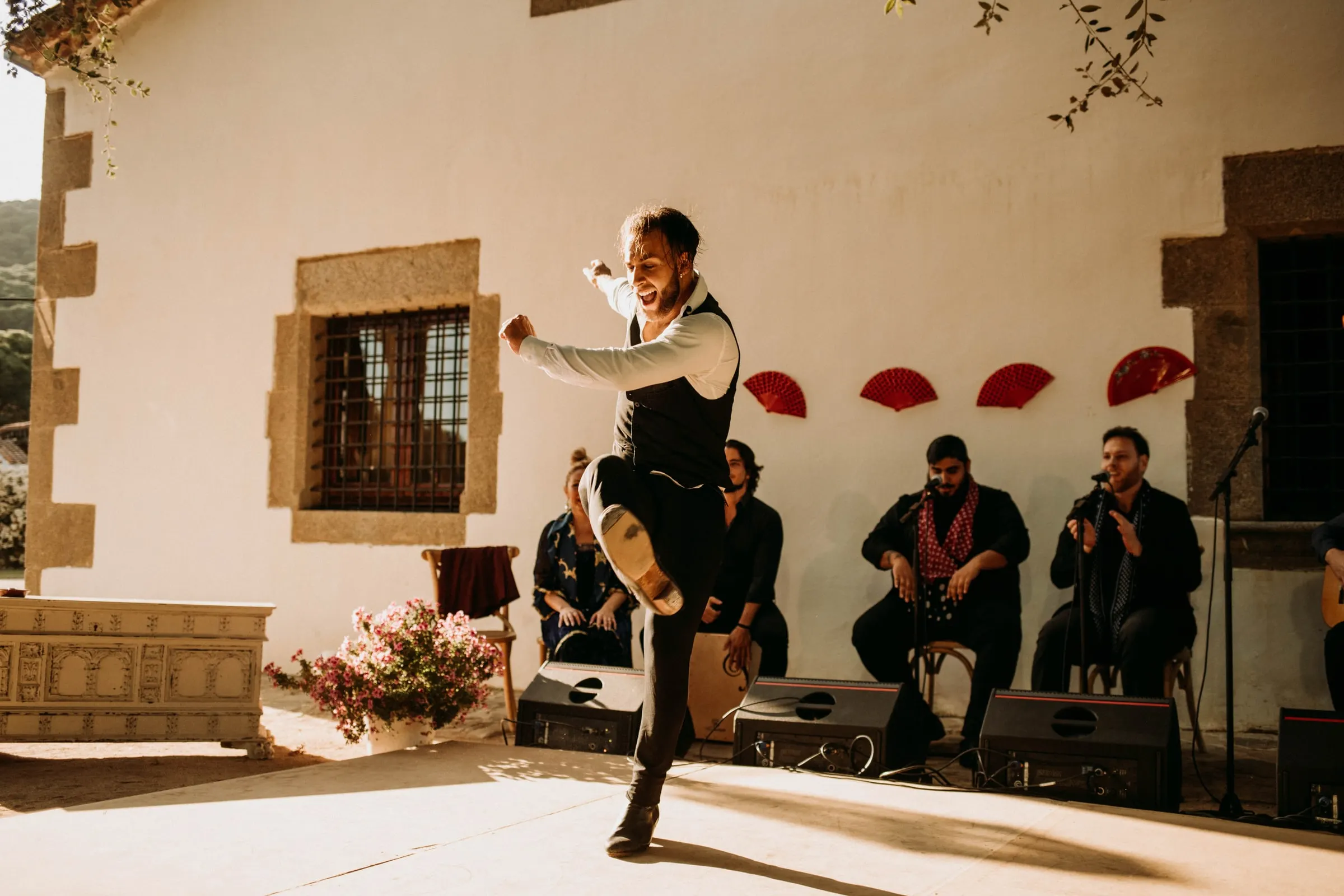 Un bailaor salta frente a los músicos y los abanicos rojos en el patio de una masía de Girona