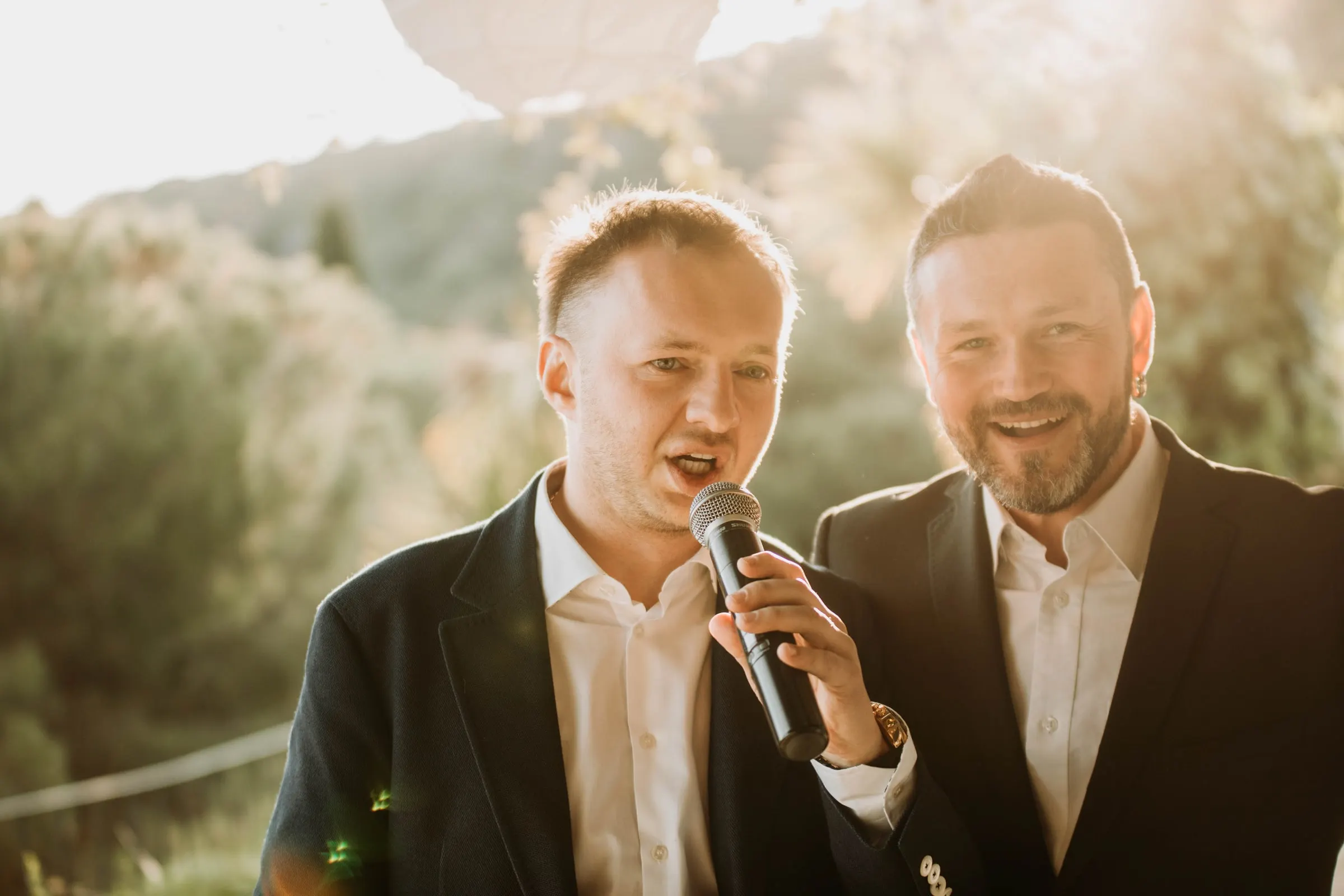 El novio y un amigo cantan juntos al micrófono durante los brindis en una masía de Girona