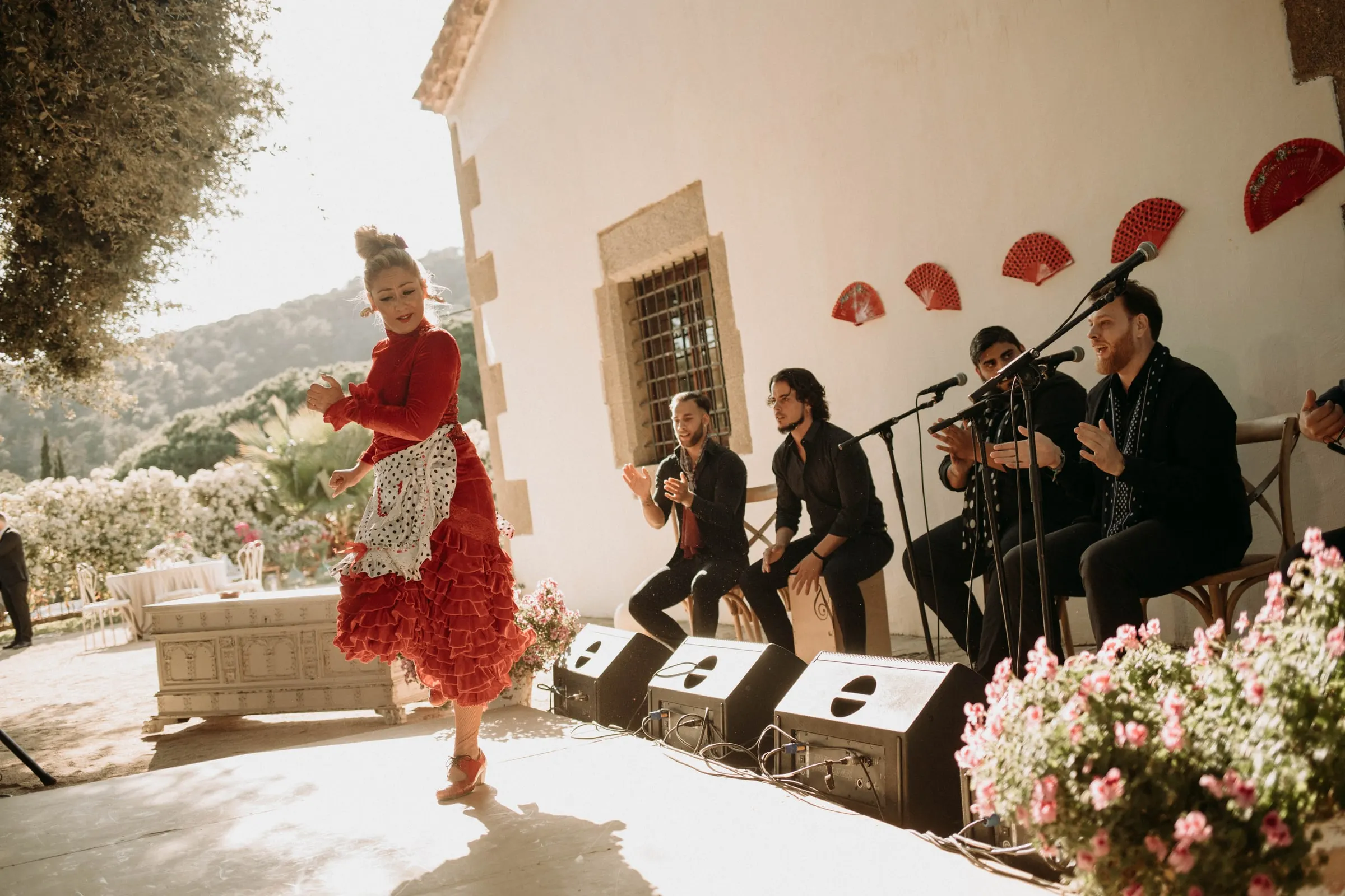 Una bailaora con vestido rojo de volantes actúa con los músicos en el patio de una masía de Girona