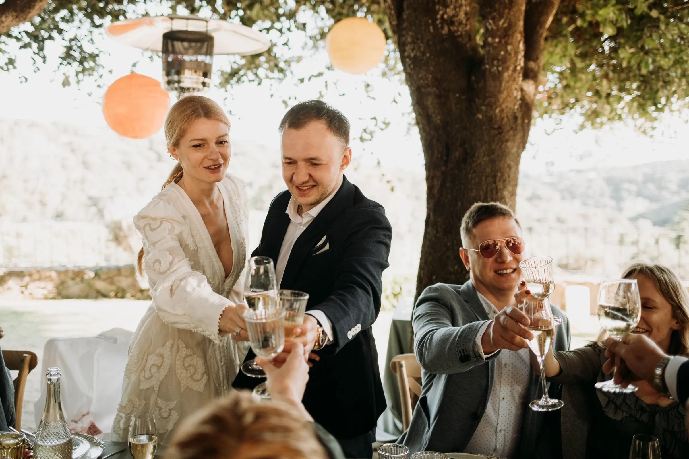 Los novios brindan con los invitados de pie alrededor de la mesa en una masía de Girona